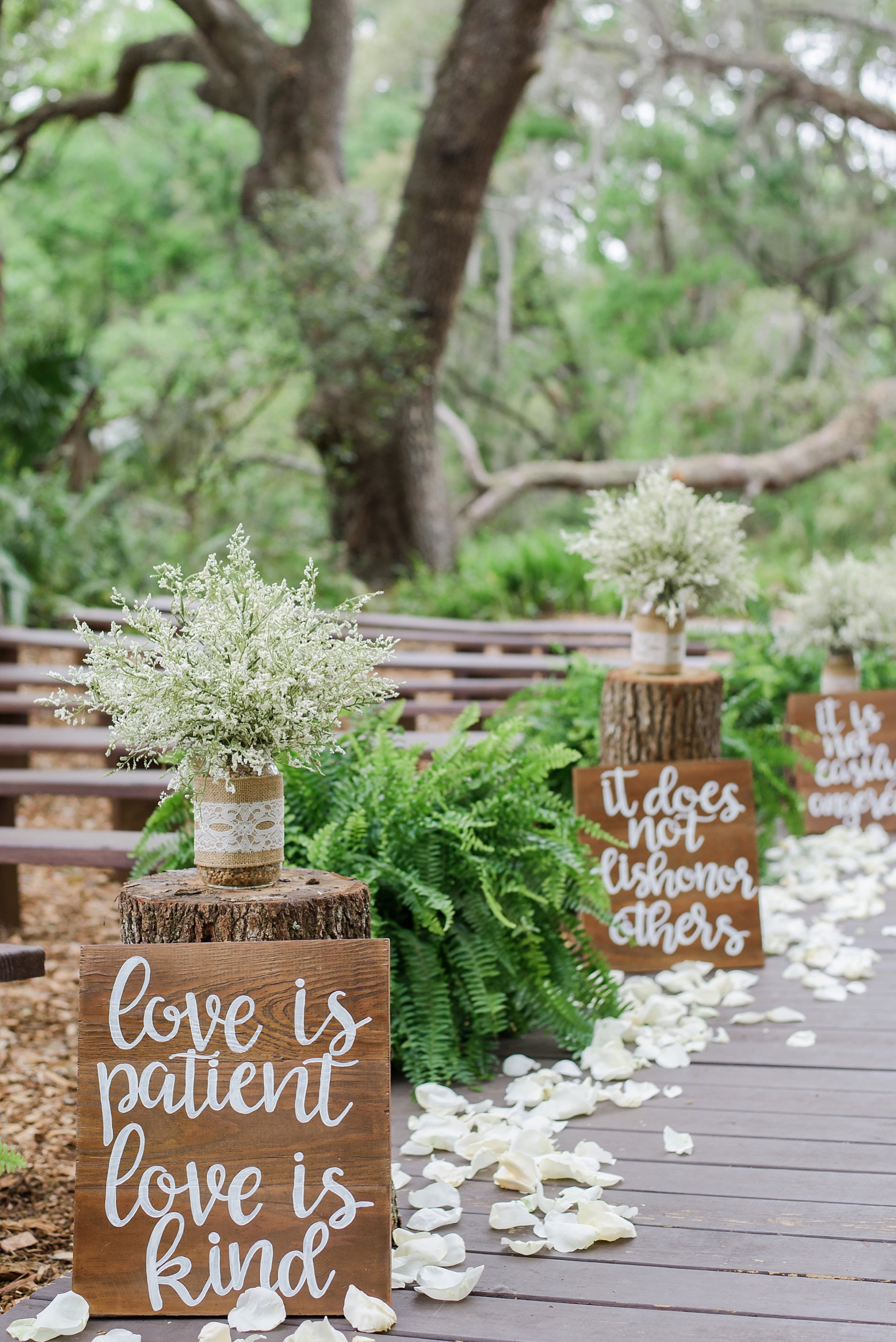 Rustic forest wedding aisle with handwritten signs and baby's breath florals