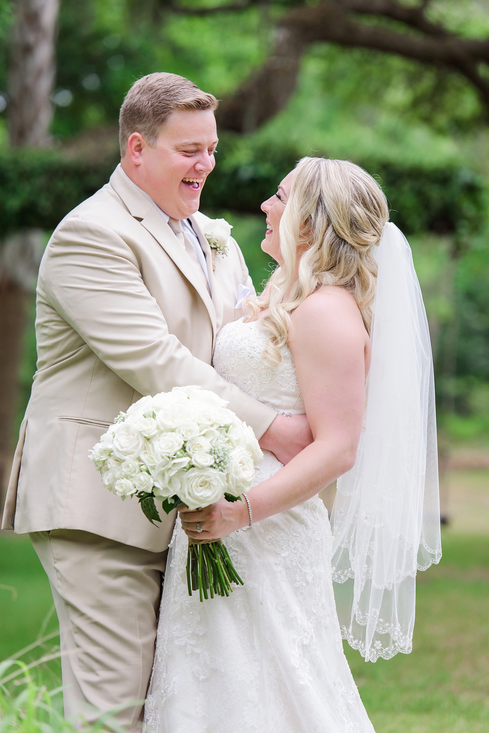 Large white bouquet of roses and the groom laughing during the wedding portraits