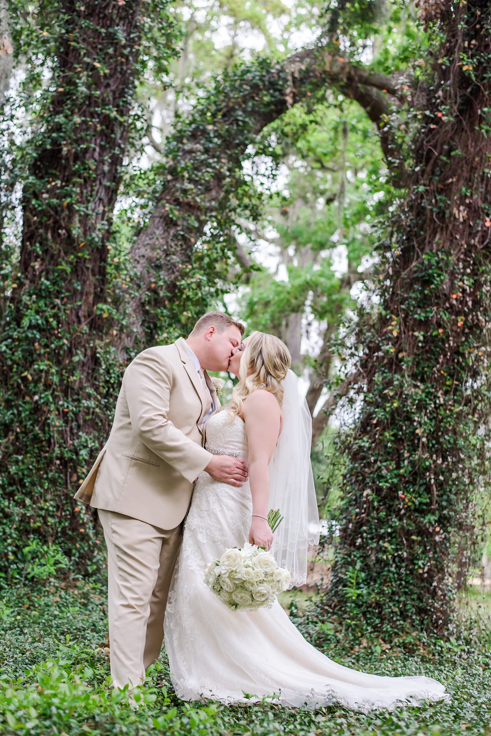 Kissing bride and groom under the old oak trees of Cross Creek Ranch