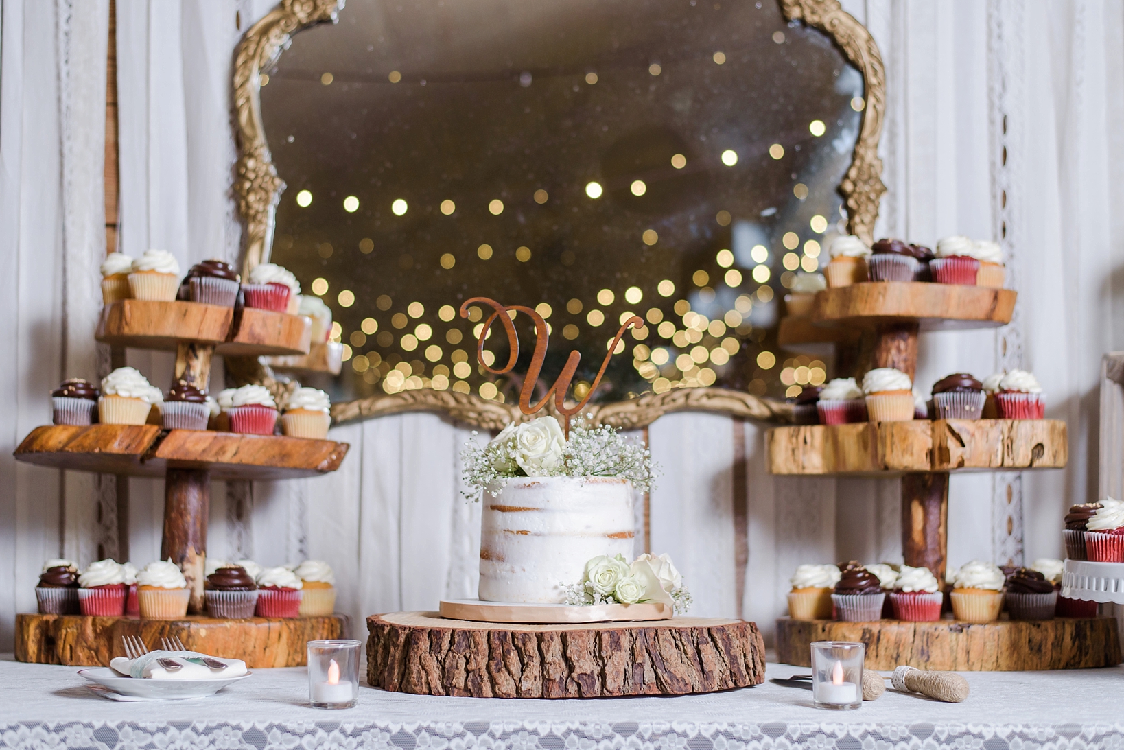 Wedding cake and cupcakes against a rustic mirror during the wedding reception by Sarah and Ben Photo
