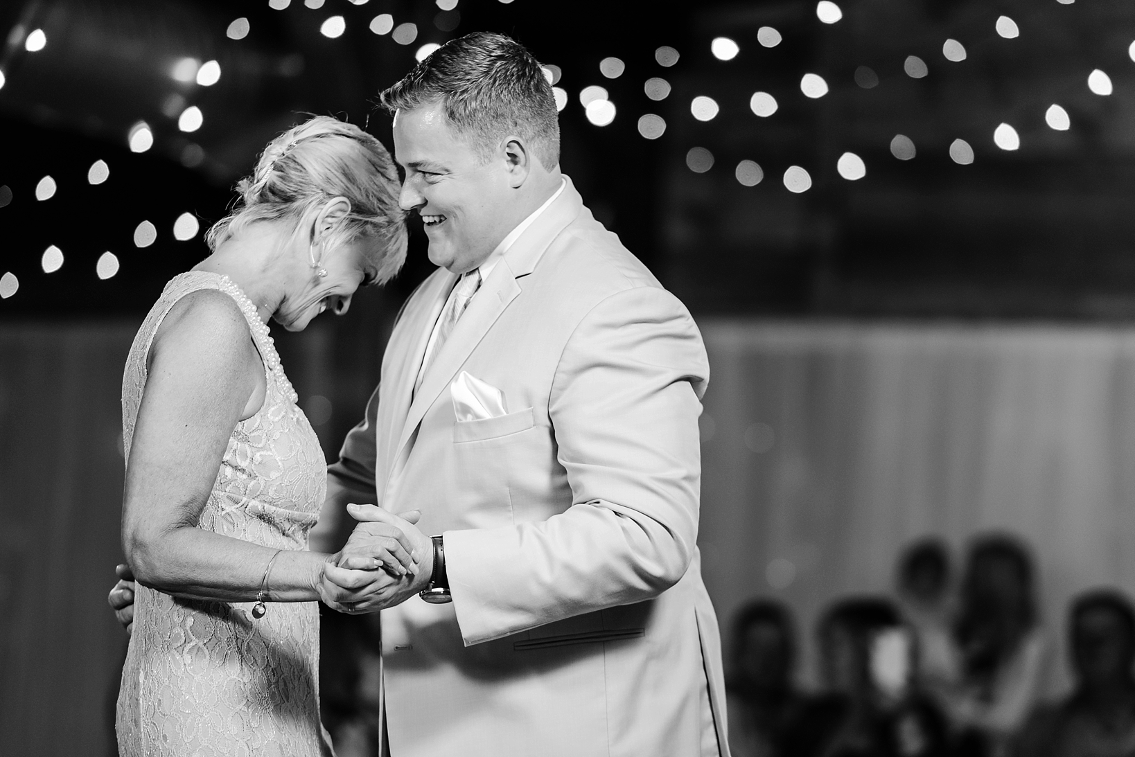 Mother Son dance in black and white with string lights in the background during the cross creek ranch reception