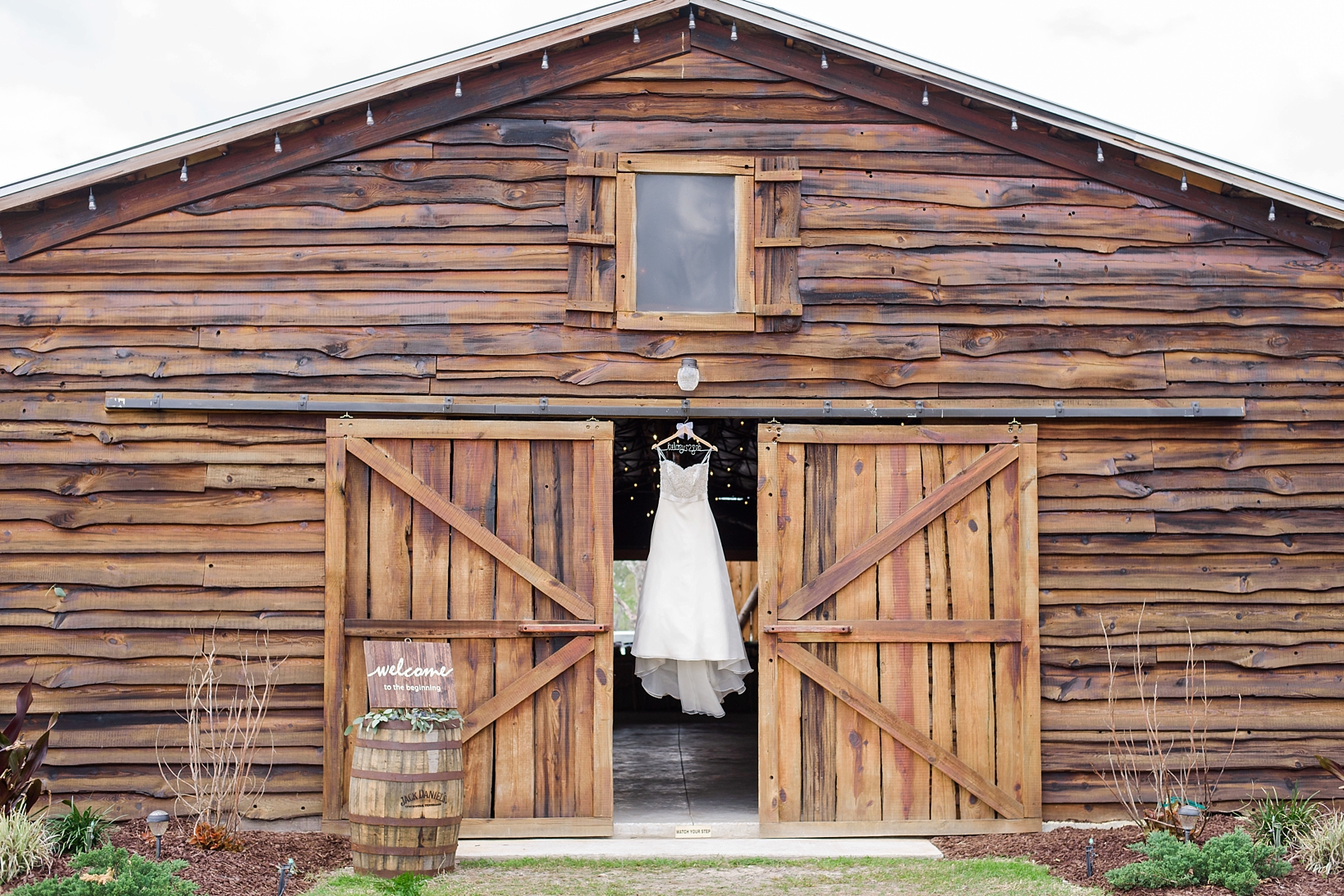 Wedding dress hanging in the doors of the rustic barn in Plant City, FL
