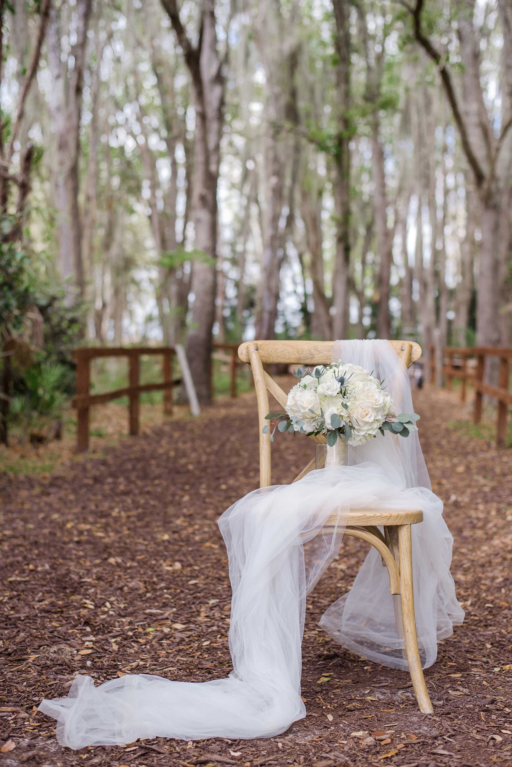 Bride's wedding bouquet in a rustic forest setting surrounded by her veil