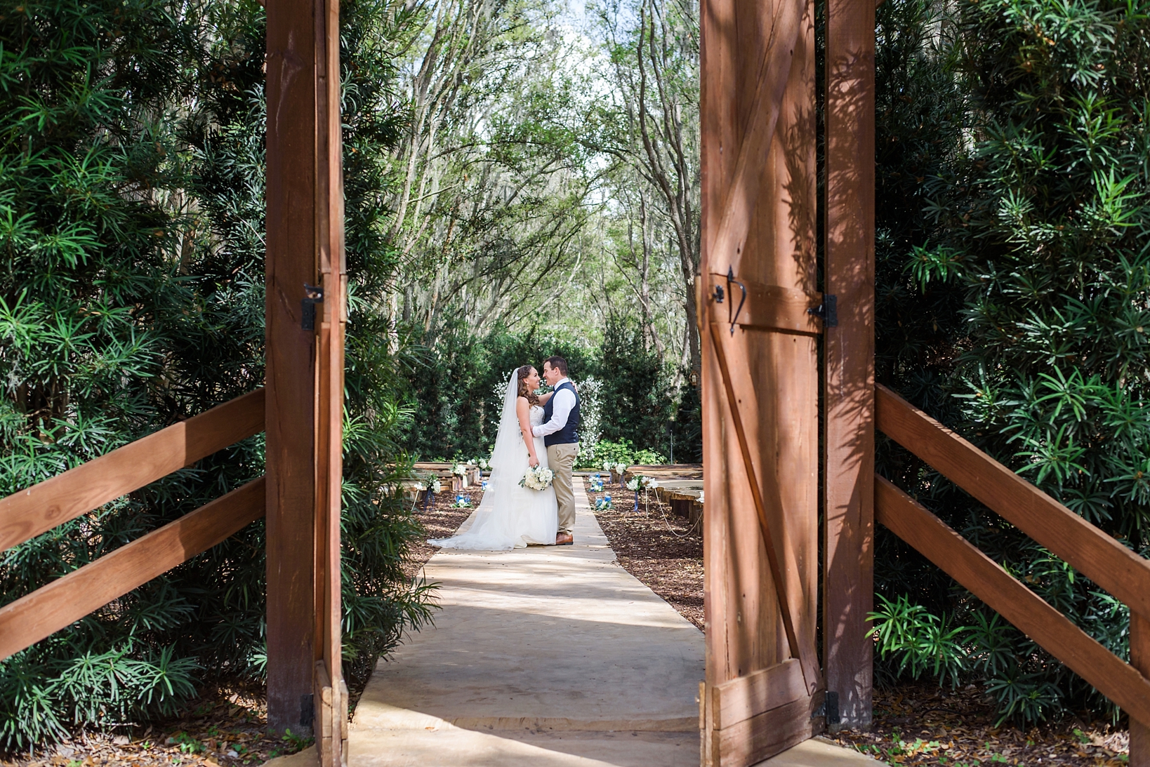 Wedding portraits of the bride and groom seen through a door that opens toward the ceremony