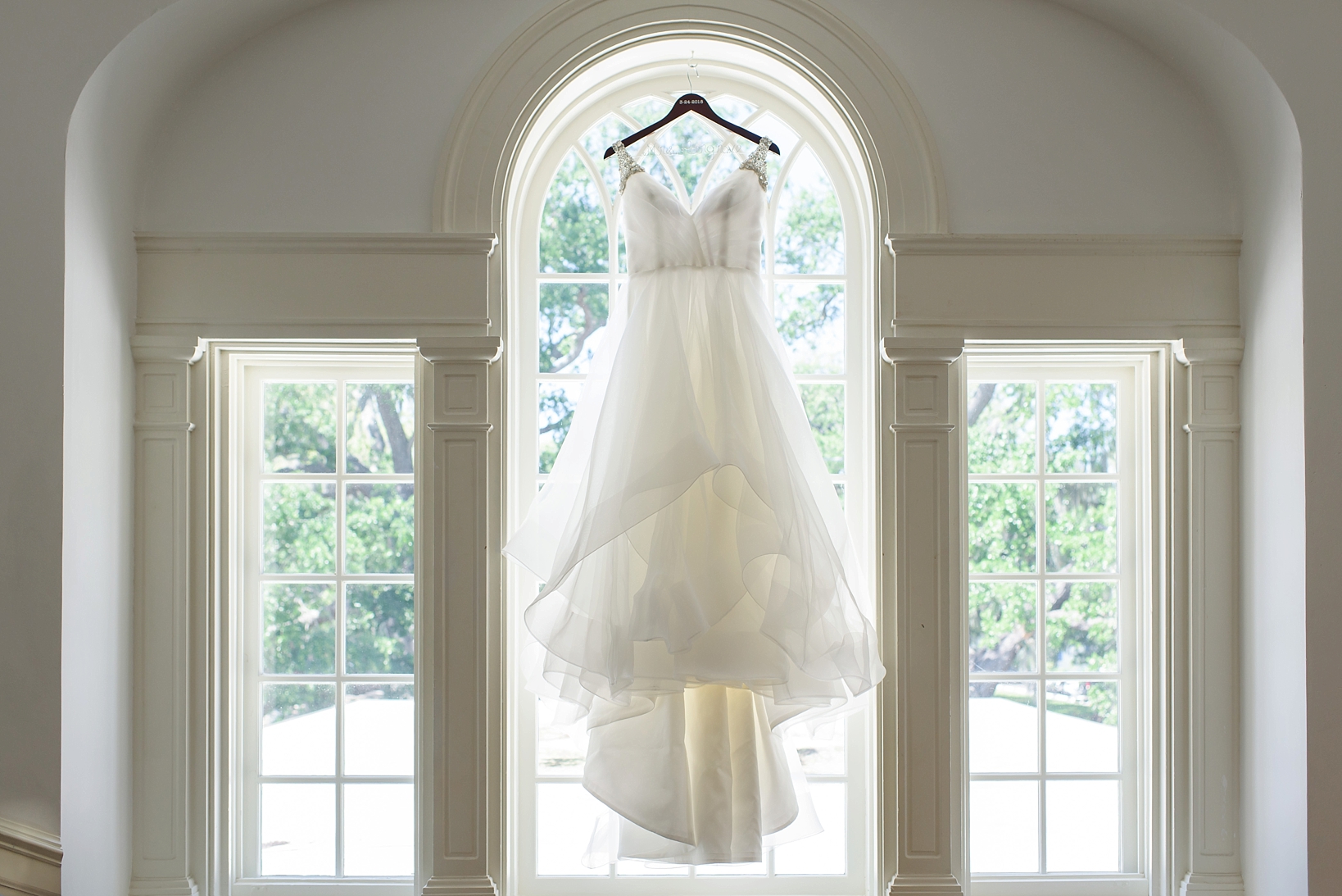 The wedding dress in an ornate window at the Tampa Yacht and Country club by Sarah & Ben Photography
