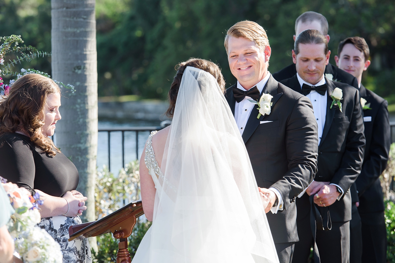 Groom smiling as his Bride reads her vows to him during the ceremony by Sarah & Ben Photography