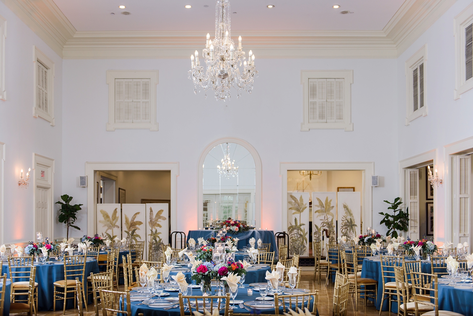 Wedding reception space inside the Tampa Yacht and Country Club with chandeliers and navy tablecloths by Sarah & Ben Photography