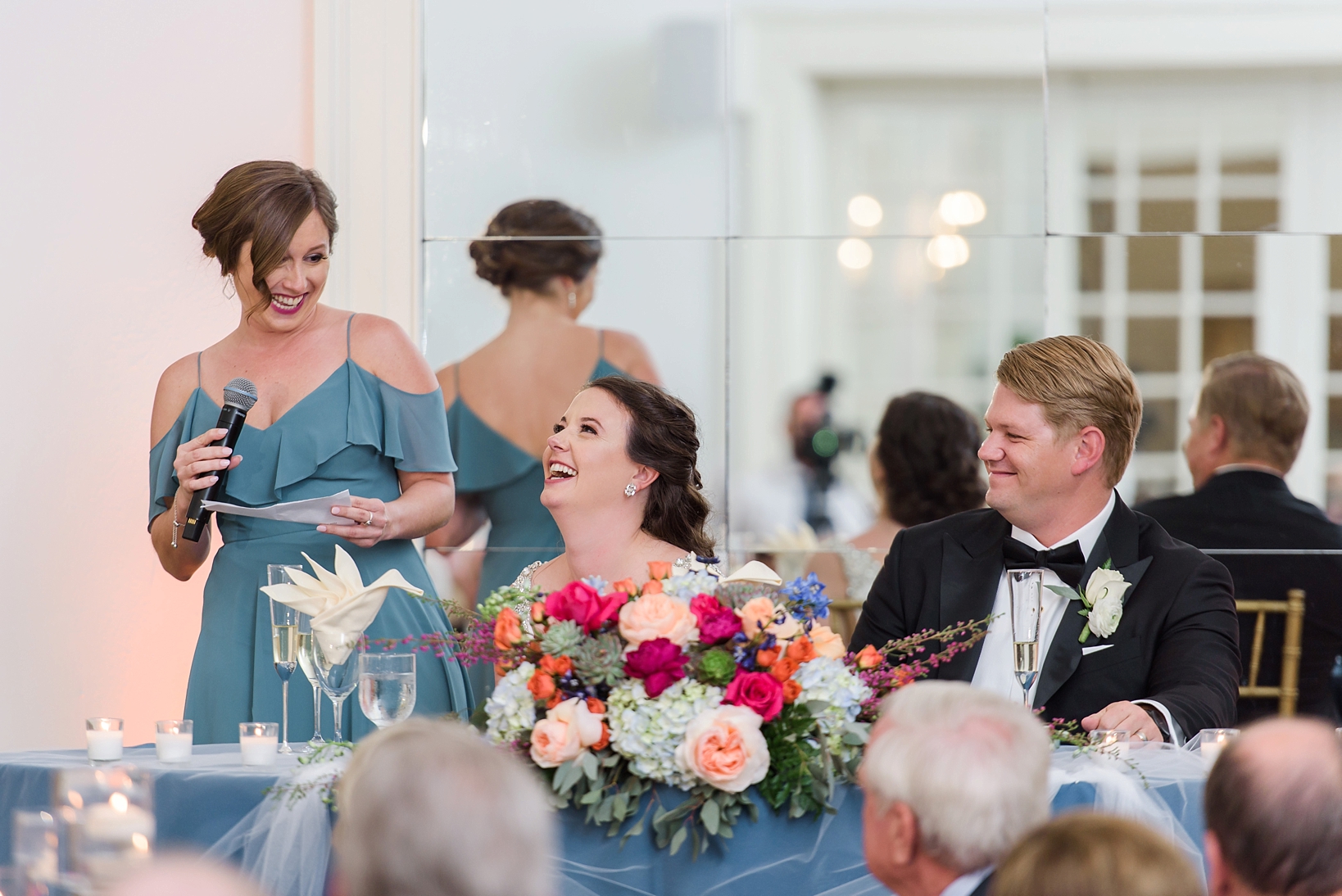 Maid of Honor giving her speech as the bride & groom laugh by Sarah & Ben Photography