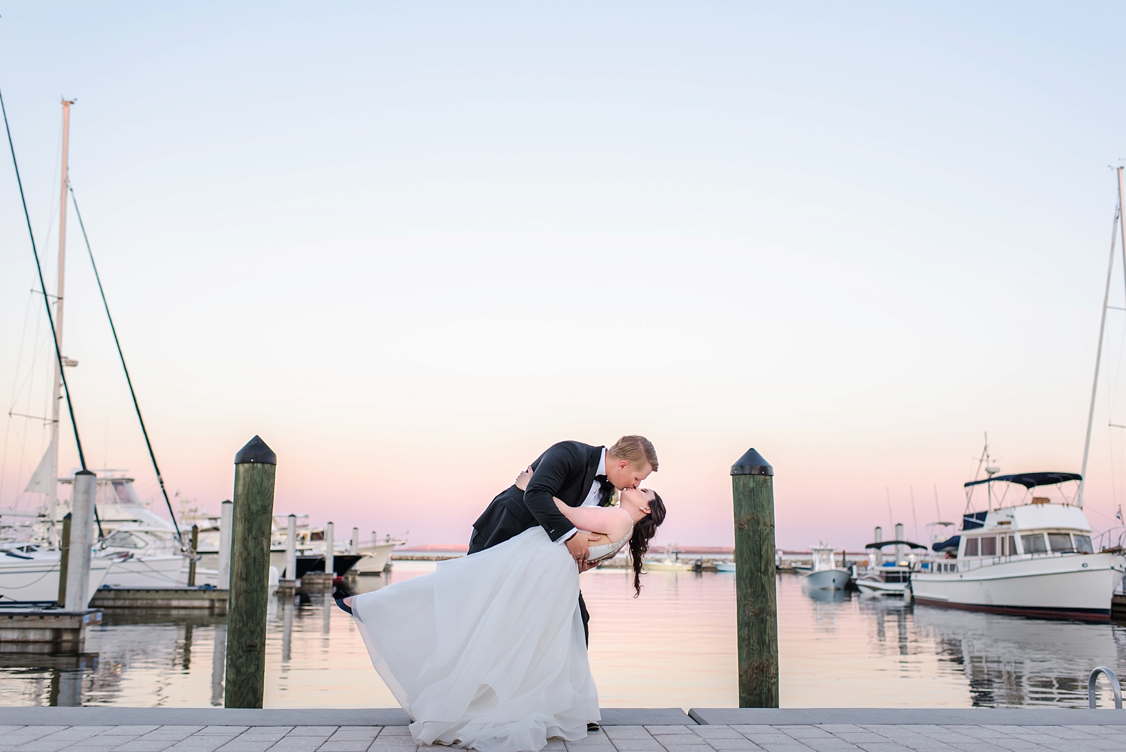 Stunning sunset with the Bride and Groom dip kissing by Sarah & Ben Photography