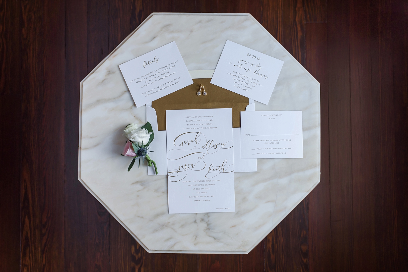 Marble table with wedding invitation suite and grooms floral boutonniere 