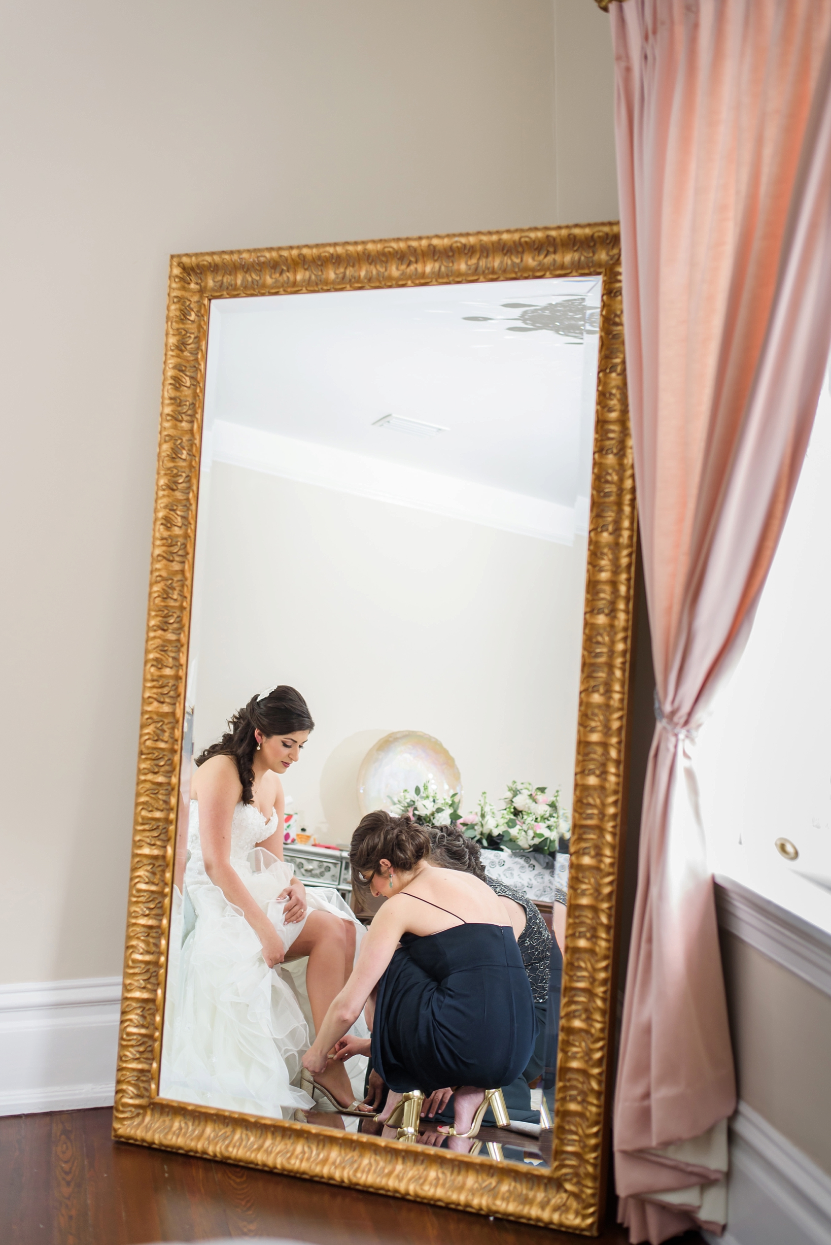 Bride and her bridesmaids in a gold framed mirror