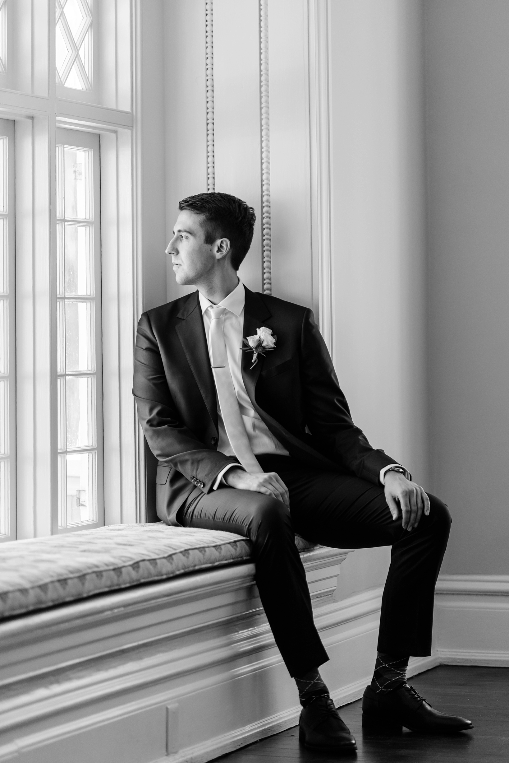Groom looking out the window in classic black and white by www.sarahben.com