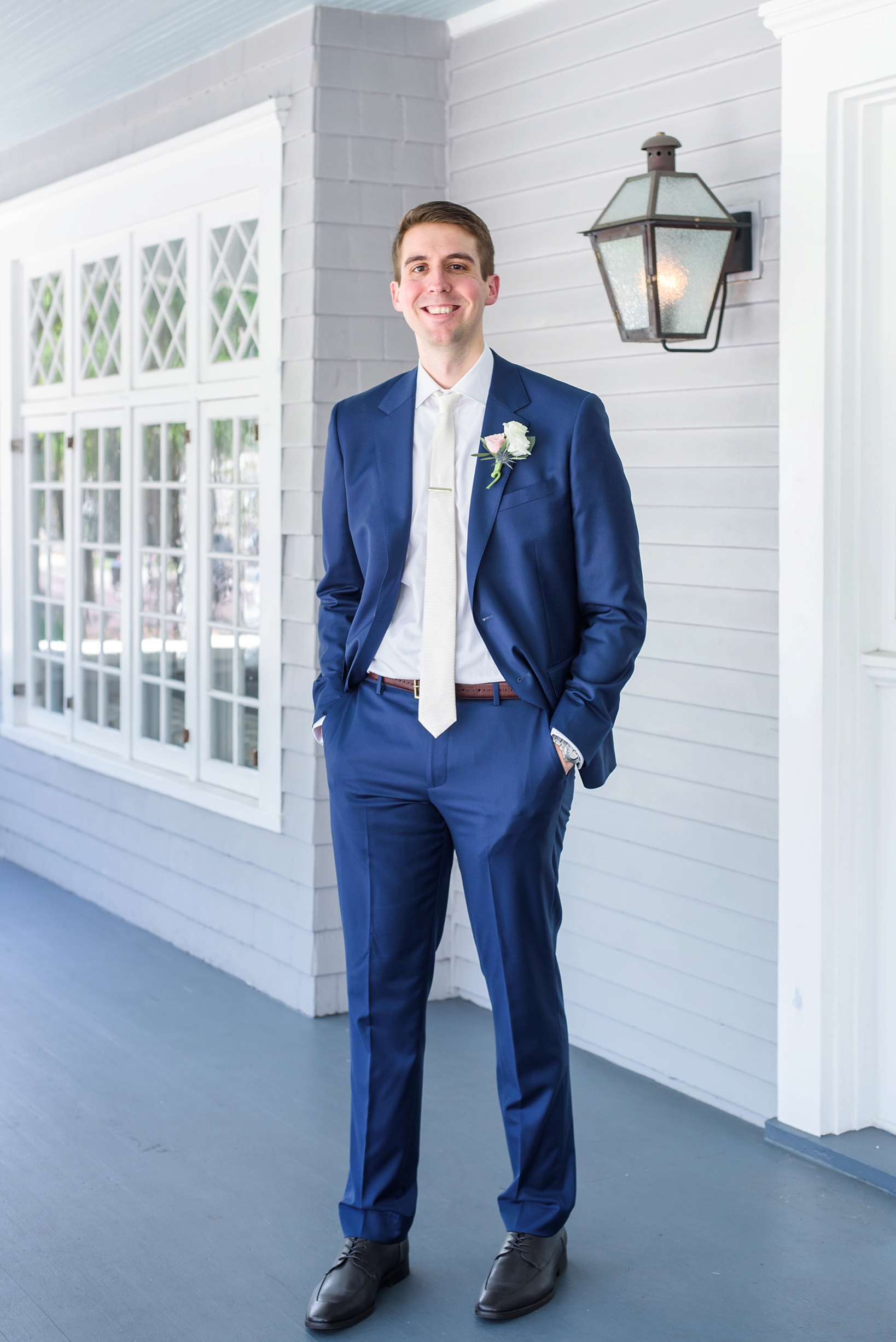 The groom in his navy suit on the front porch of the Orlo in Tampa Florida