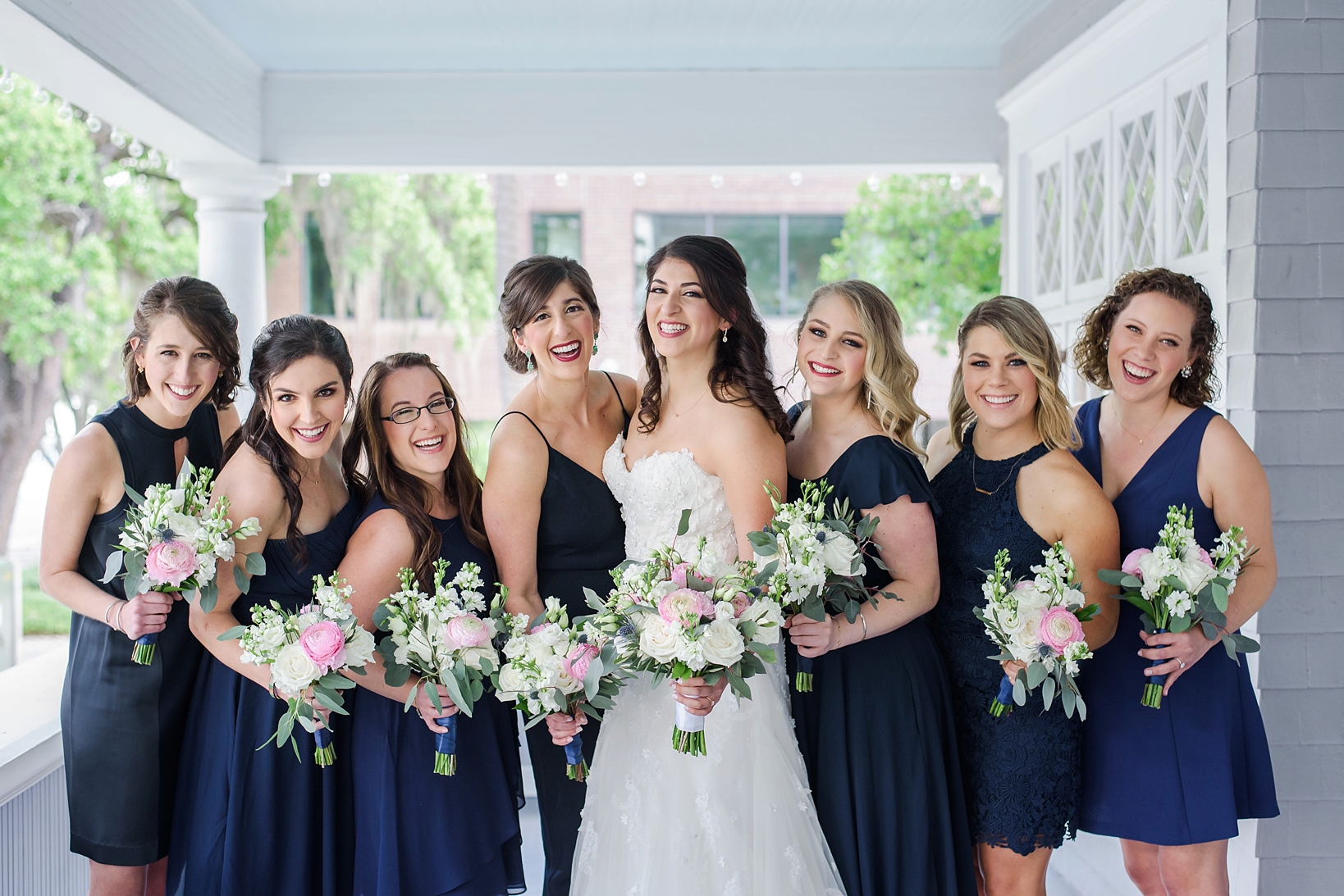 Beautiful Bride and Bridesmaids holding their floral bouquets in navy blue dresses