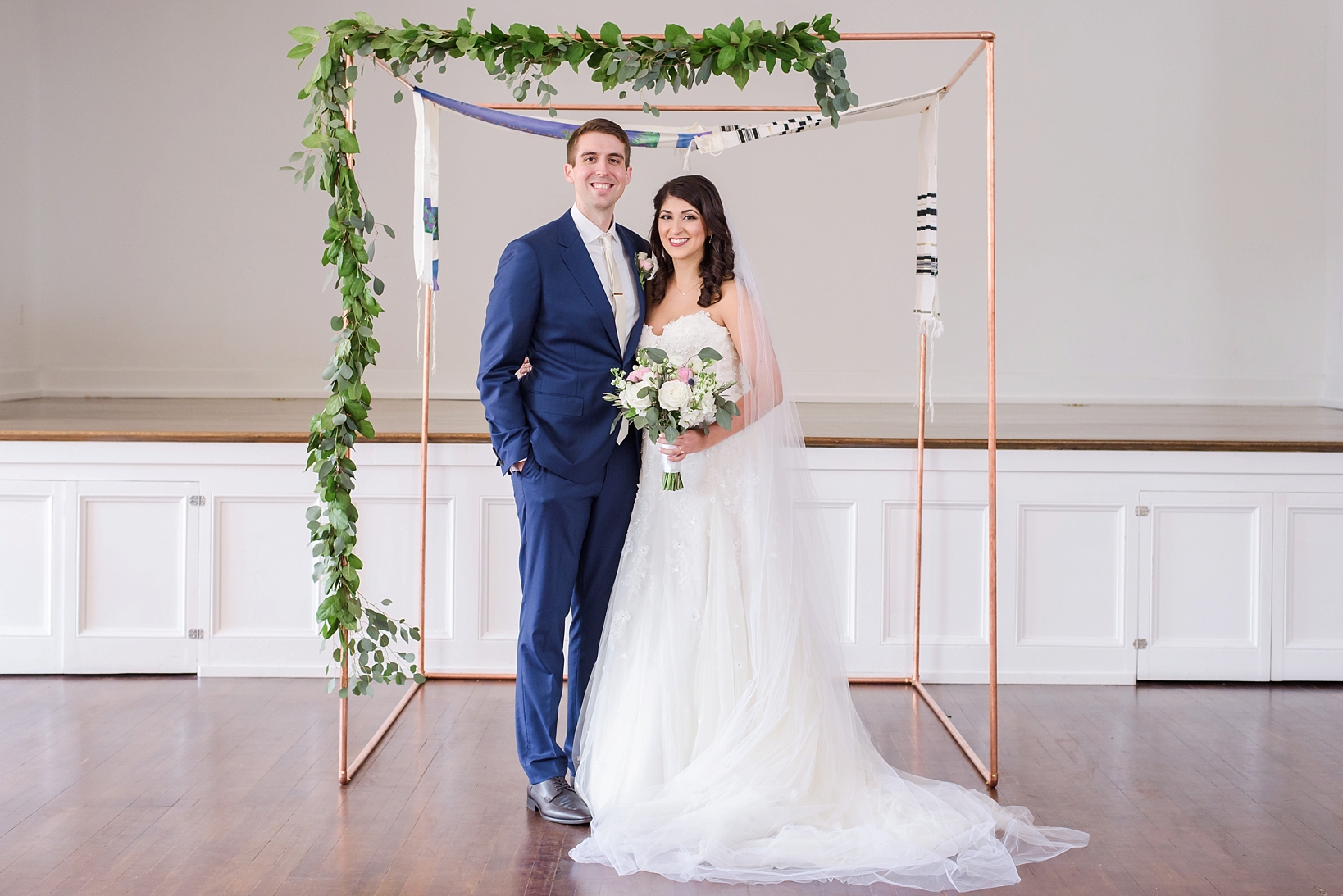 Bride and Groom pose for a classic image under their custom huppah