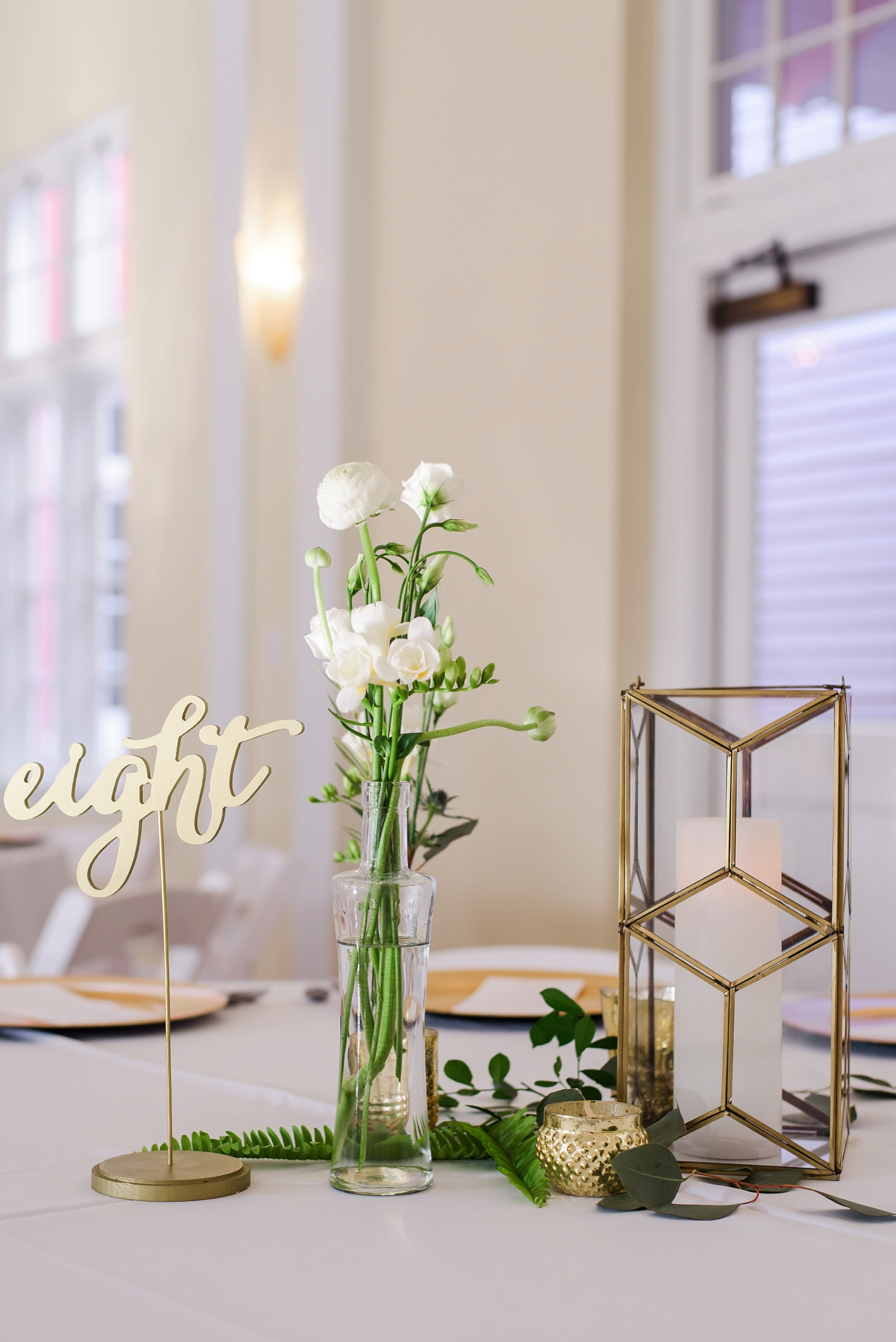 Gold accented candle holders and wood-cut lettered table numbers