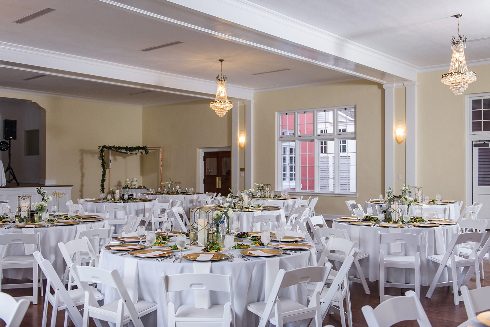 The wedding reception space with gold chargers and greenery accents