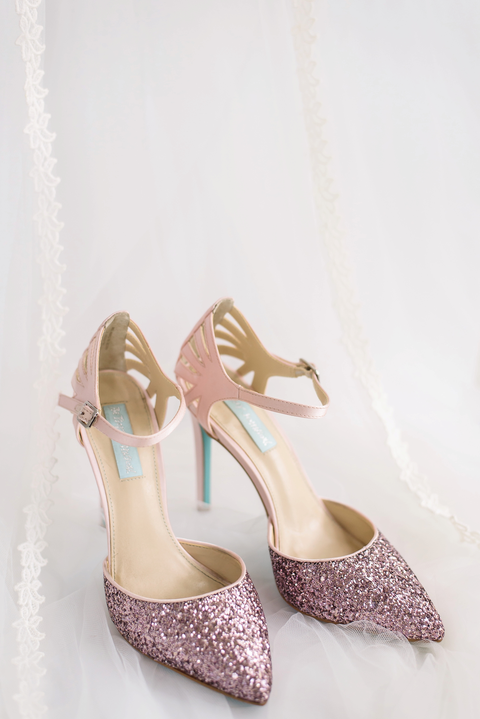 The Bride's pink glitter Betsey Johnson wedding shoes with her mothers veil as a backdrop.