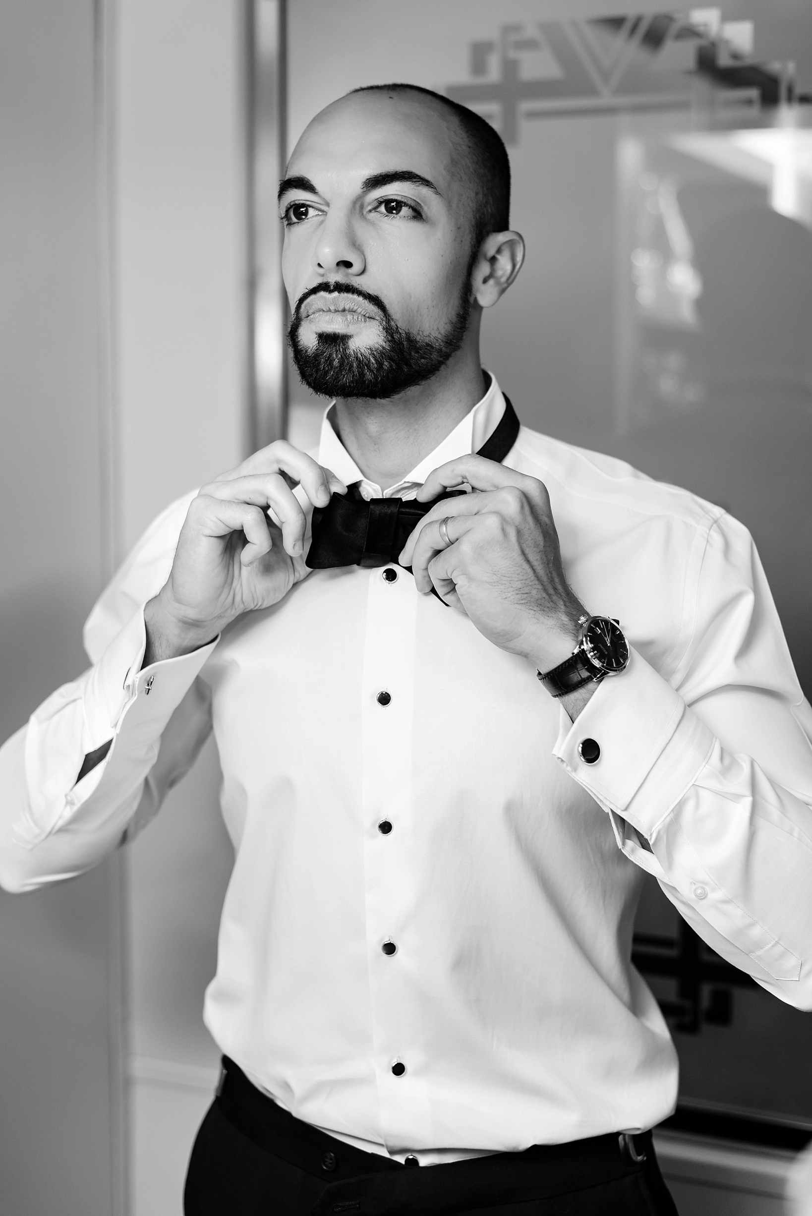 Groom adjusting his bowtie in classic Black and White by Sarah & Ben Photography