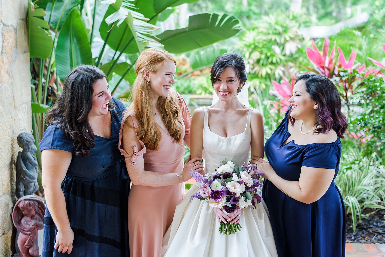 Bride and her bridesmaids smiling in front of a garden right before the wedding ceremony by Sarah & Ben Photography