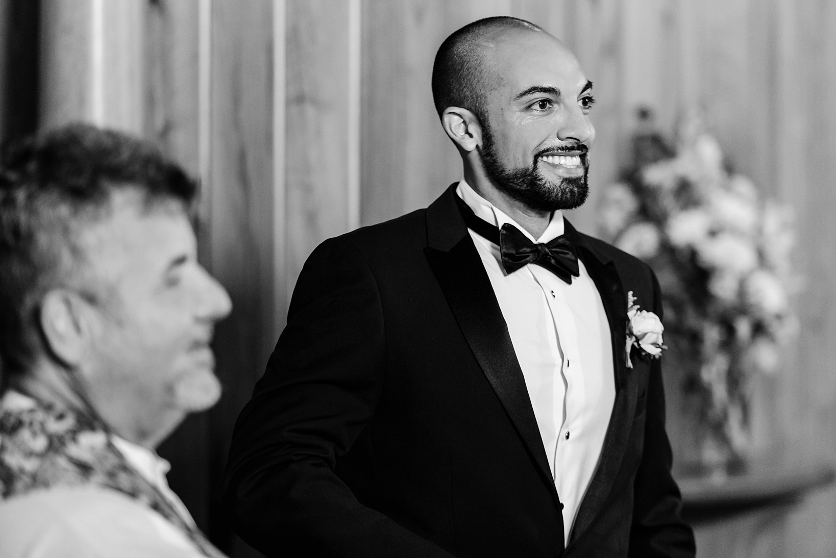Groom smiling as he sees his bride for the first time walking down the aisle by Sarah & Ben Photography