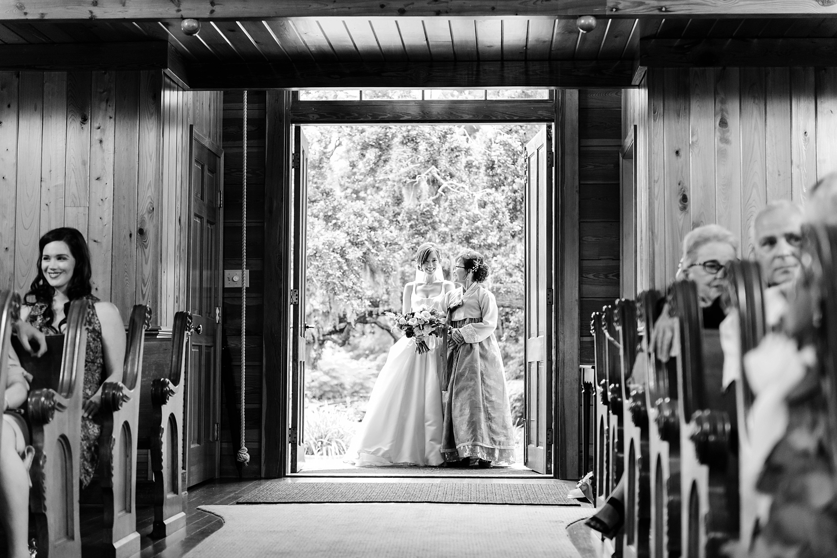 The bride enters the wedding chapel with her mom in black and white by Sarah & Ben Photography