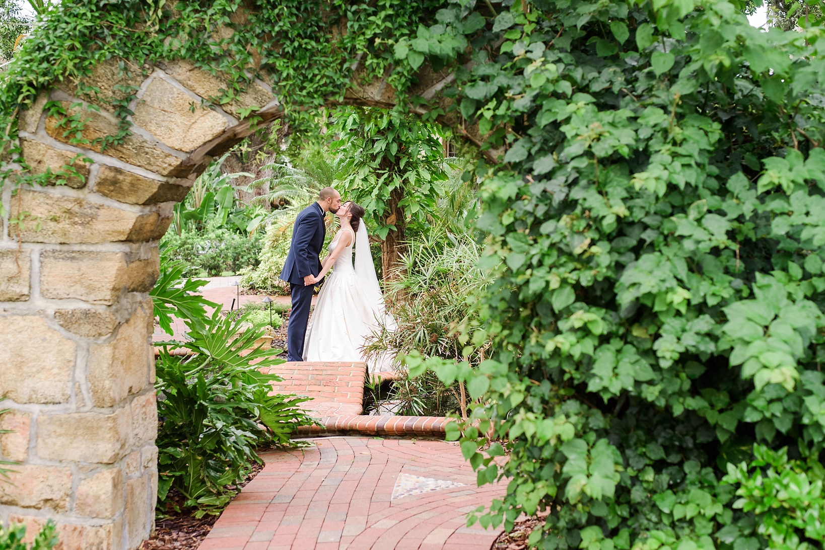 Bride and Groom kiss under the archway in the koi gardens by Sarah & Ben Photography