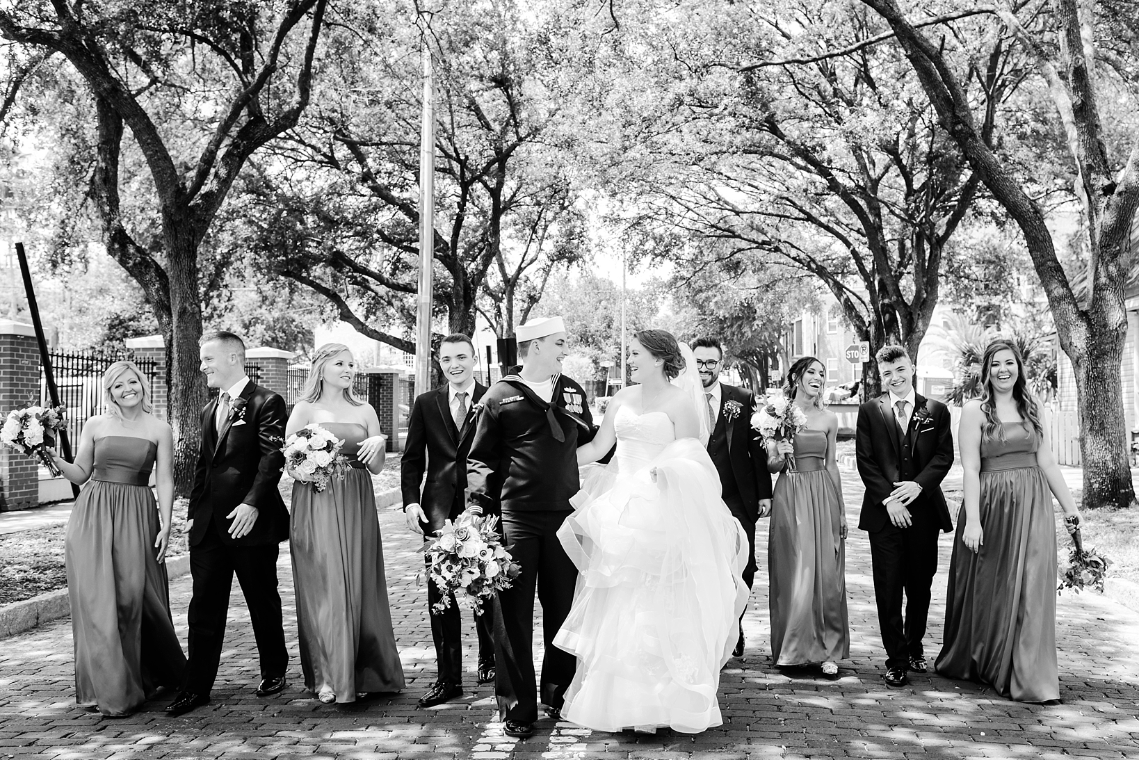 The bridal party walking down the street under the old oak trees