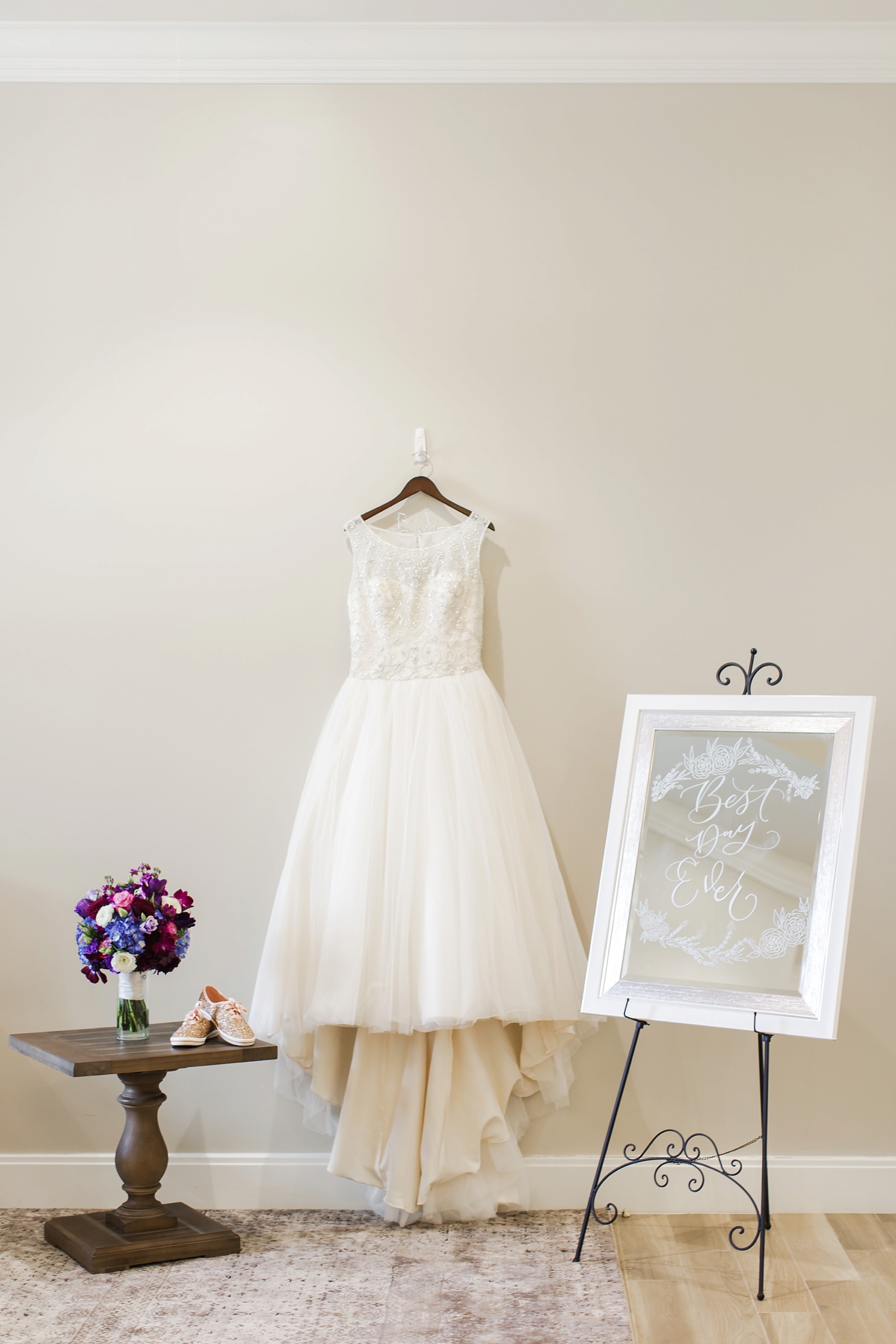 The wedding dress surrounded by the florals and custom mirror by Sarah & Ben Photography