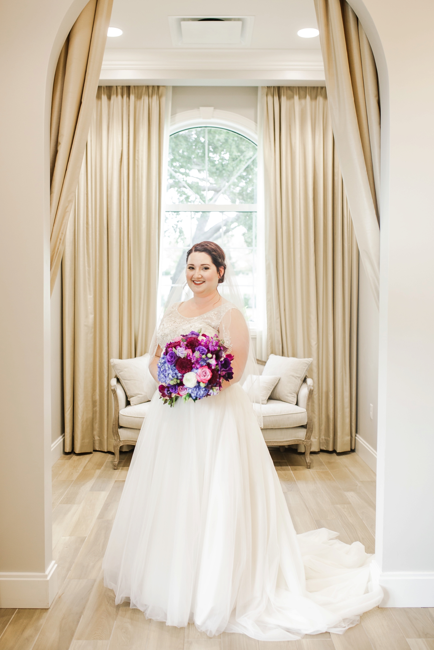The bride holding her colorful bouquet in the bridal suite of the Harborside Chapel by Sarah & Ben Photography