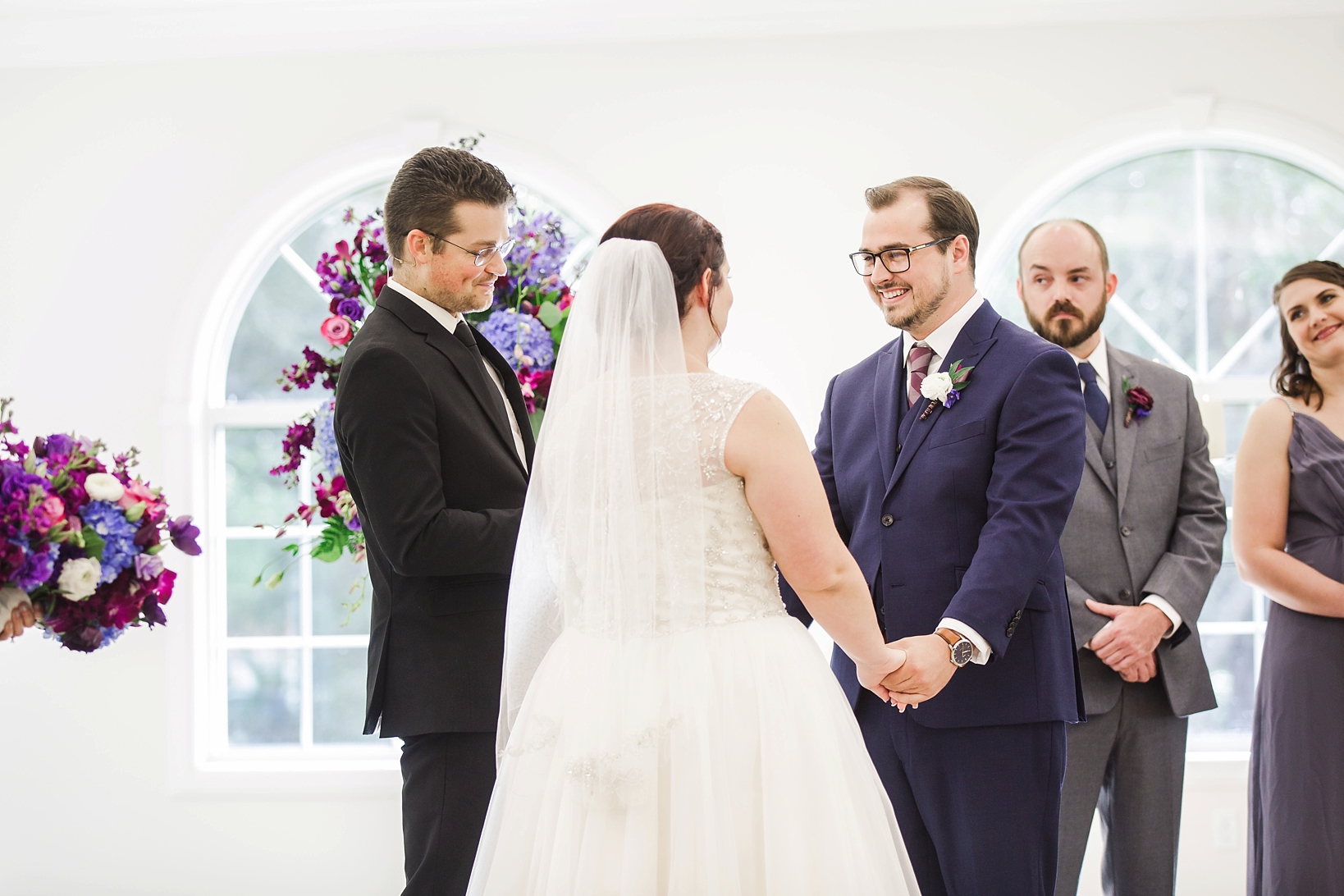 The bride and groom holding hands during the ceremony by Sarah & Ben Photography
