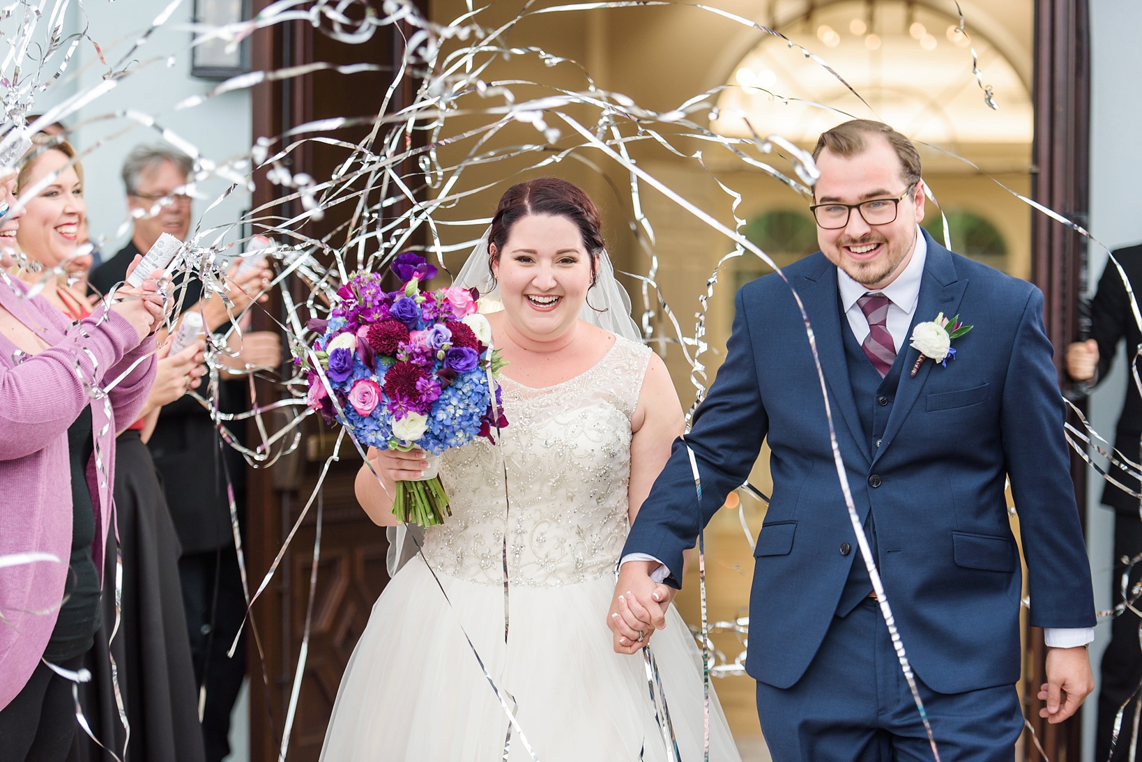 A confetti streamer exit as the bride and groom exit the chapel by Sarah & Ben Photography