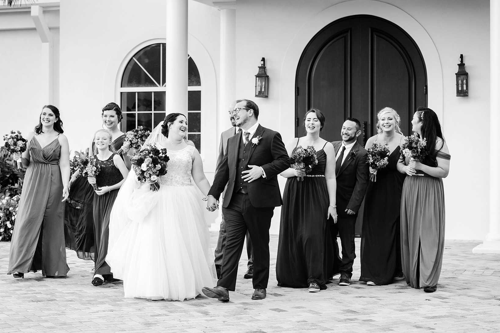 Black and white image of a bride and groom laughing outside the church by Sarah & Ben Photography