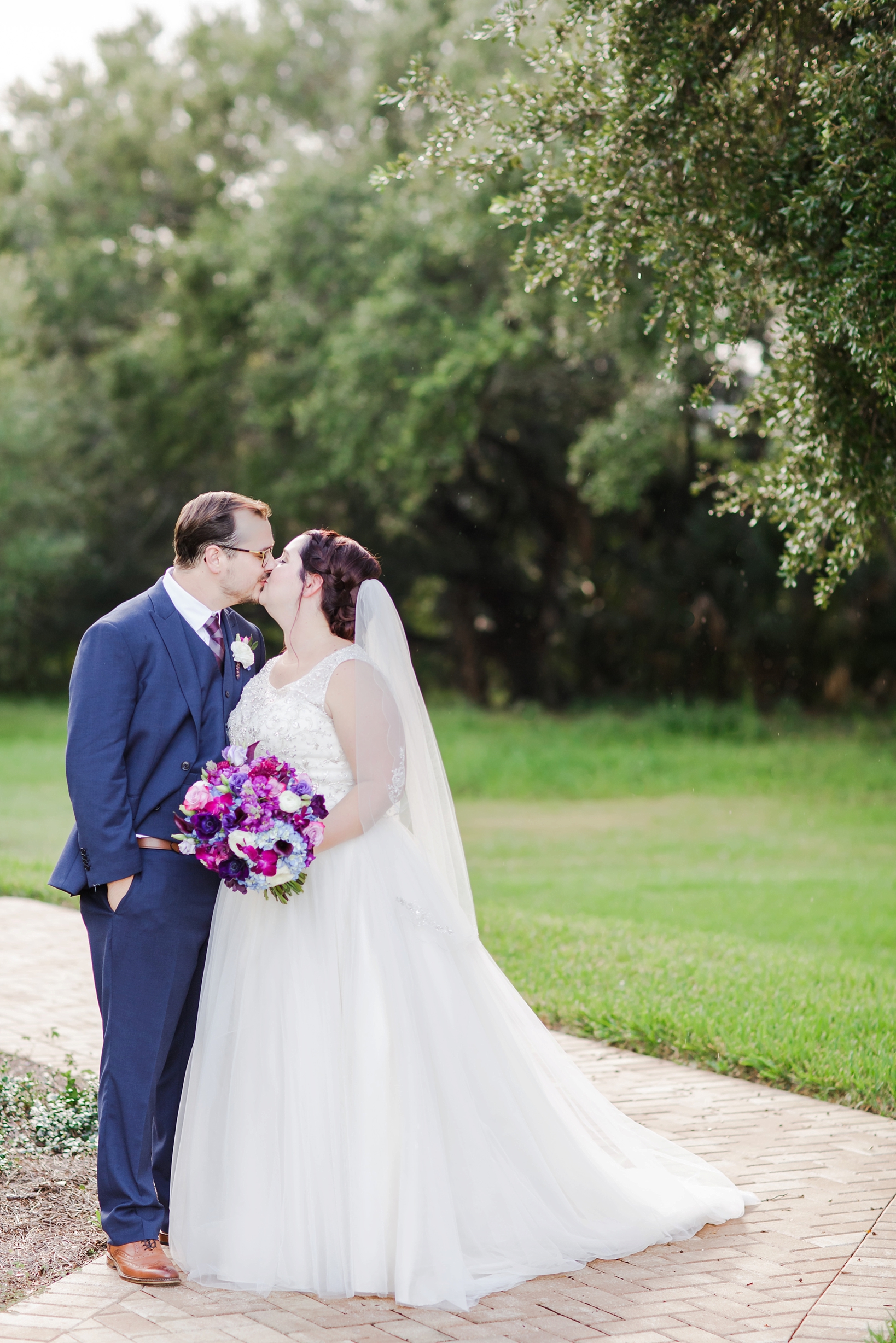 Bride and groom share a kiss on the grounds of the harborside chapel by Sarah & Ben Photography