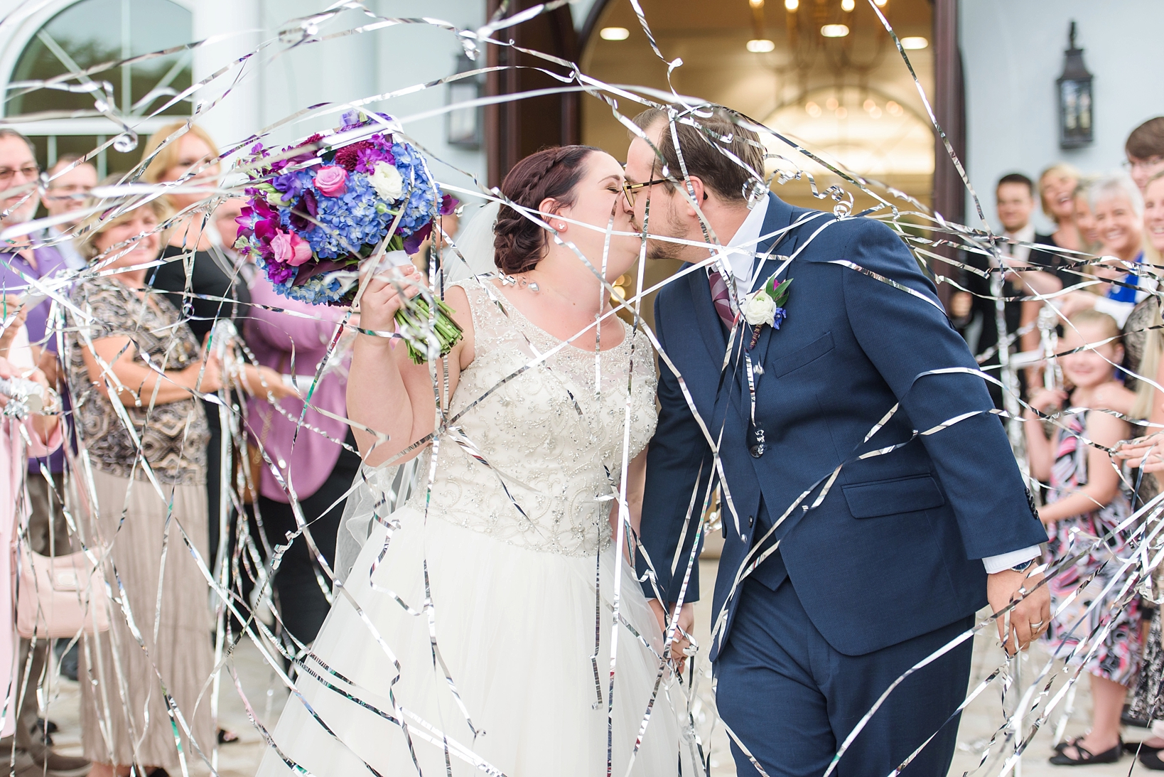 Couple kiss under the streamers as they exit the church by Sarah & Ben Photography