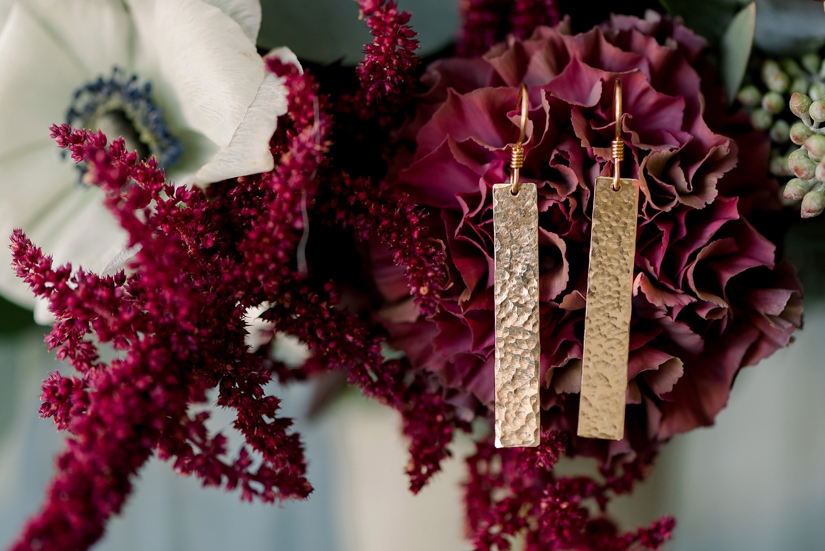 Gold bar earrings dangle from the bride's florals on her wedding day