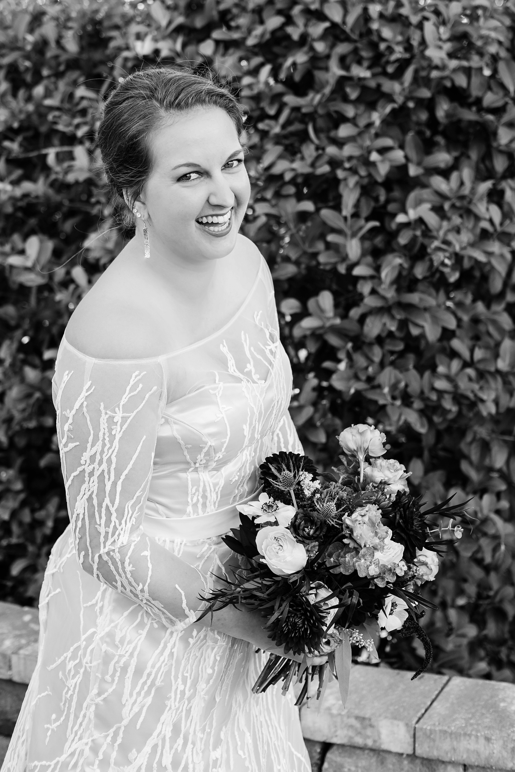 Classic black and white image of the bride posing with her flowers by Sarah & Ben Photography