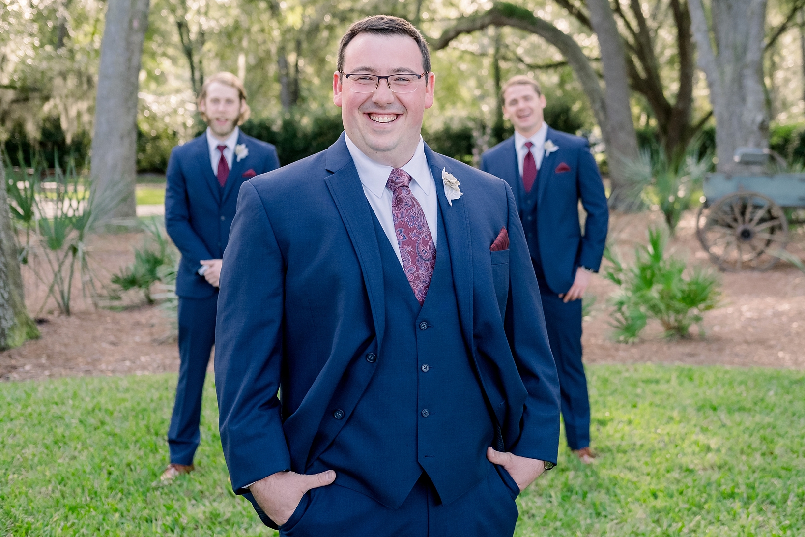 Groom smiling at the camera in a Navy Suit with red pocket square