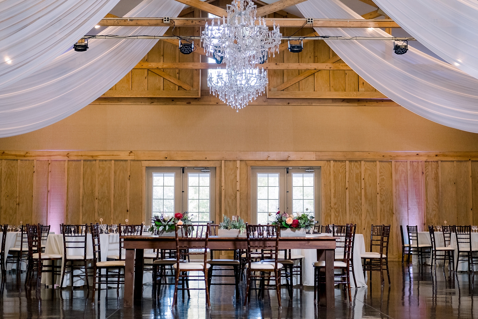 Full room shot of all the tables and chandeliers in the reception barn at Bowing Oaks Plantation