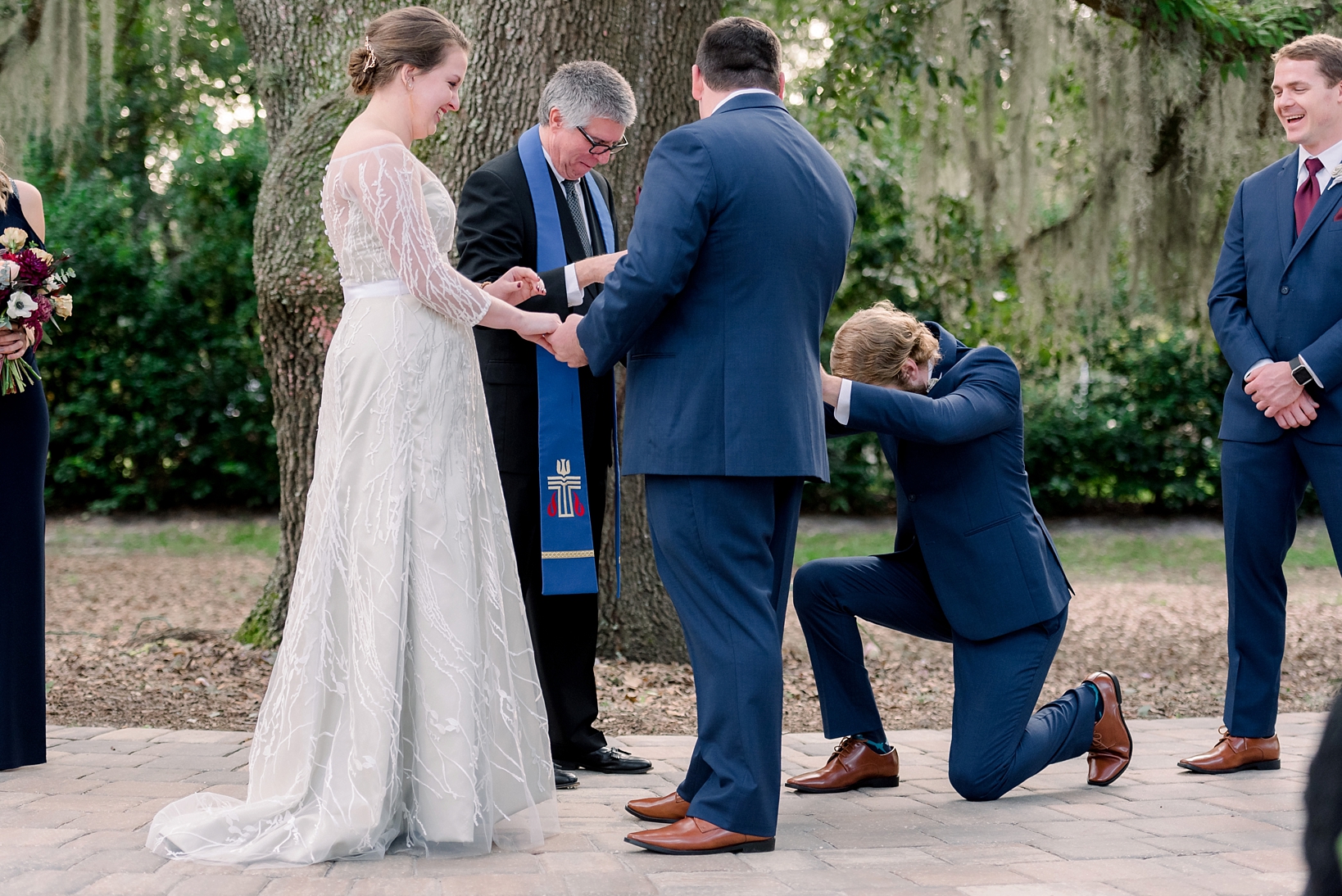 The best man knees as he hands the rings to the officiant at Bowing Oaks by Sarah & Ben Photography