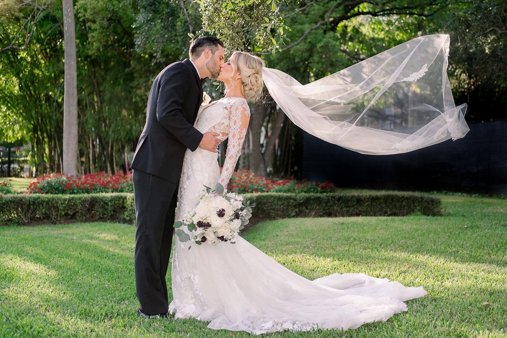 The Bride and Groom share a kiss in the gardens of the University of Tampa as the wind blows the Bride's veil by Sarah & Ben Photography