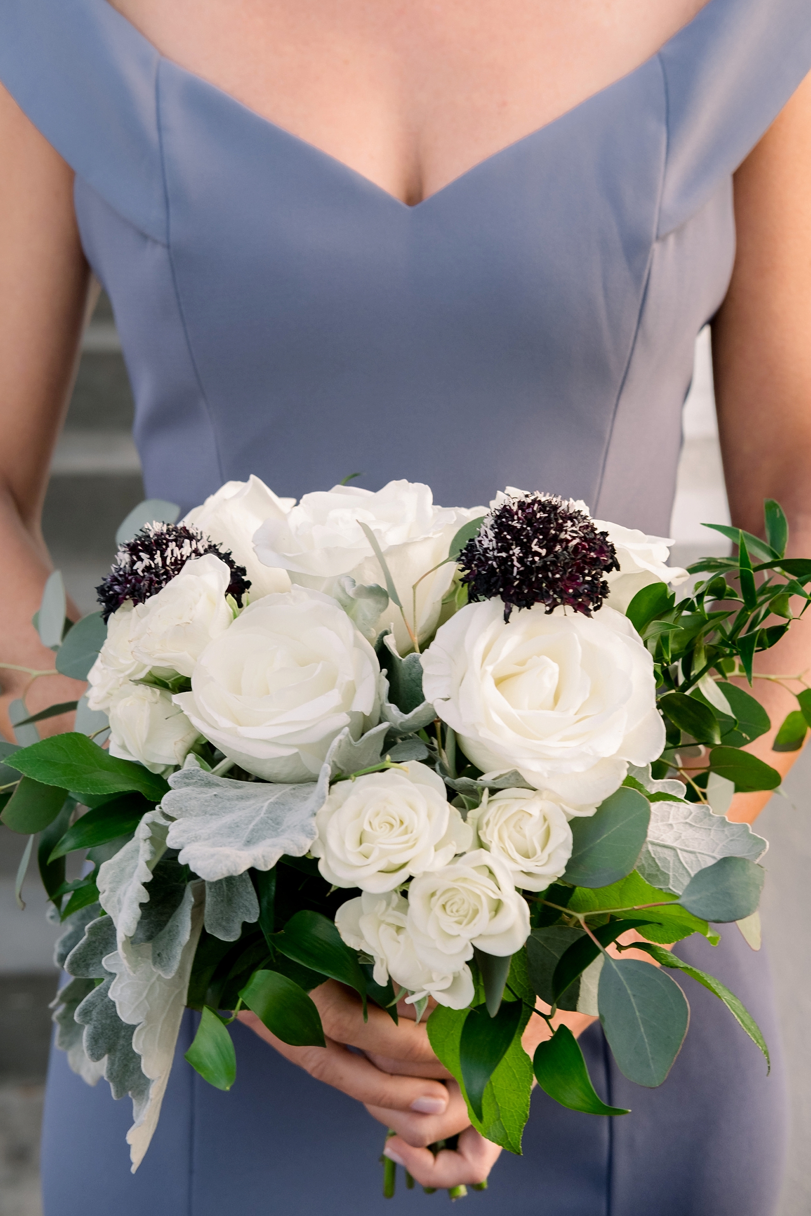 Bridesmaid holding her floral bouquet with white roses and eucalyptus leaves by Sarah & Ben Photography