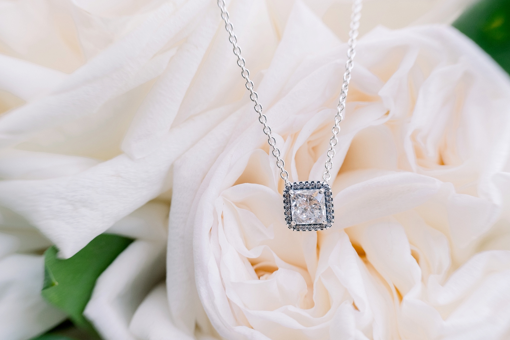 The diamond centered bridal necklace against the florals of her flower bouquet by sarahben.com