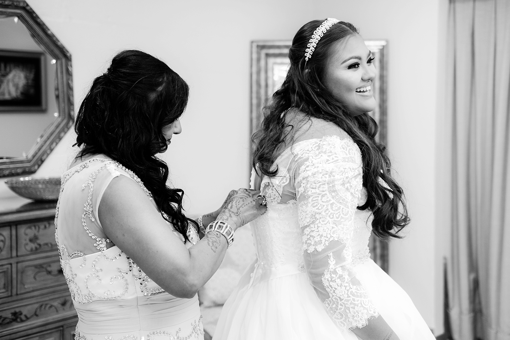 The Bride laughing as her mom buttons her into her wedding dress