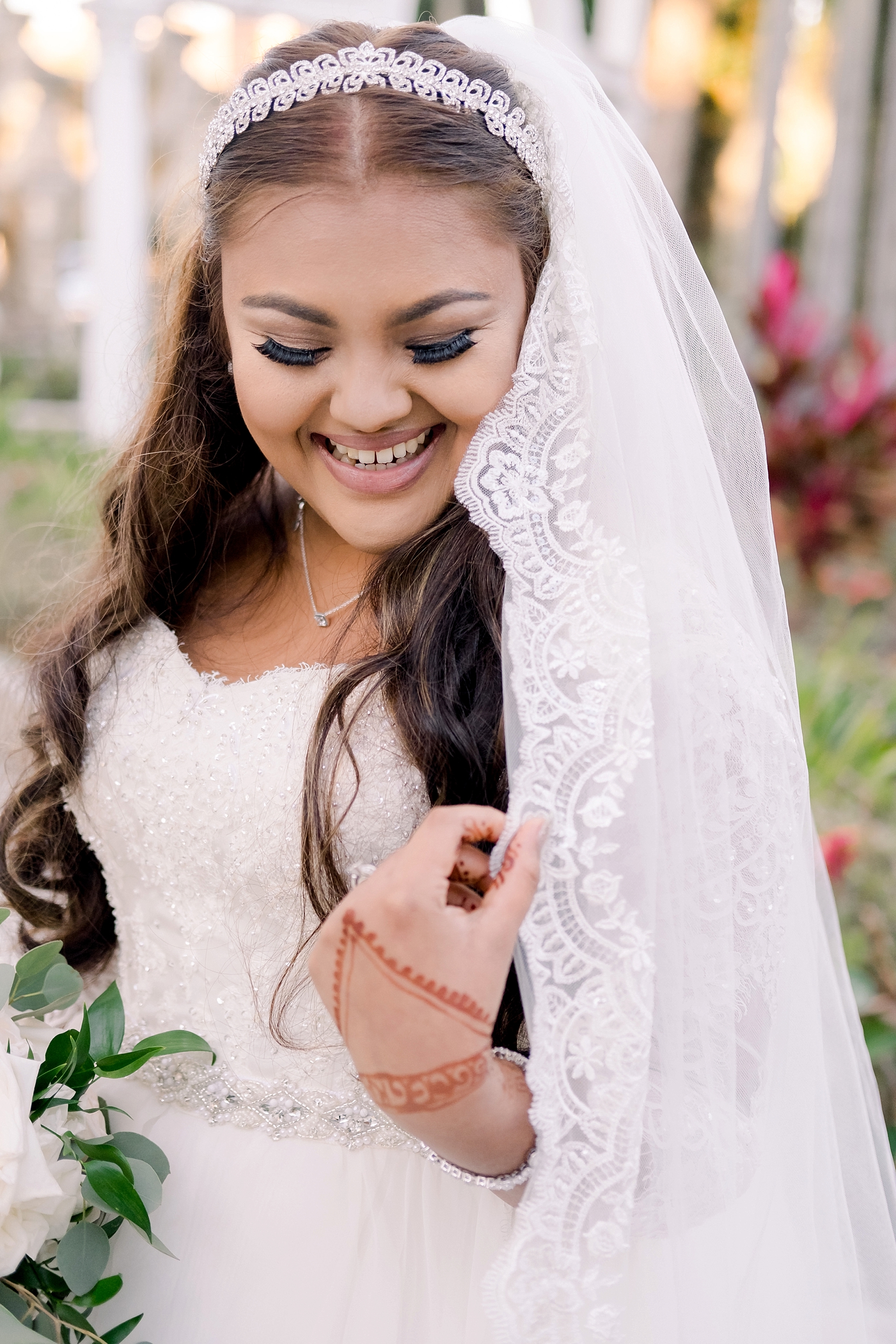 The bride laughing as she holds her wedding veil
