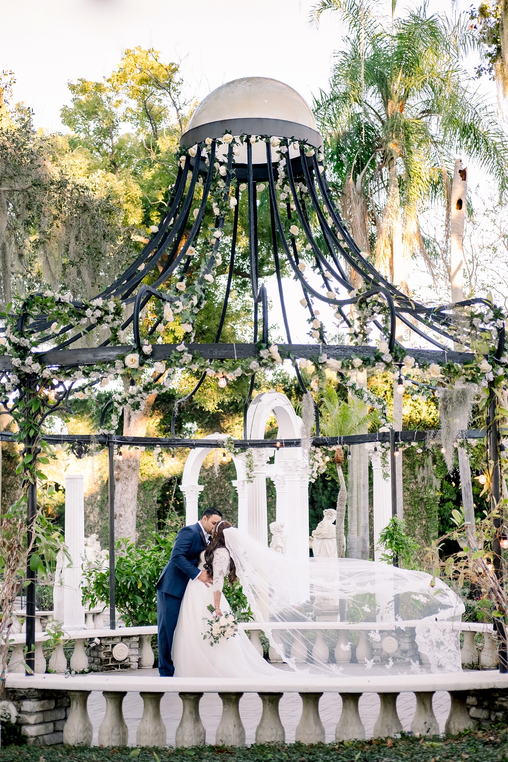 The Bride and Groom kissing under the iron gazebo at the Kapok Tree by sarahben.com