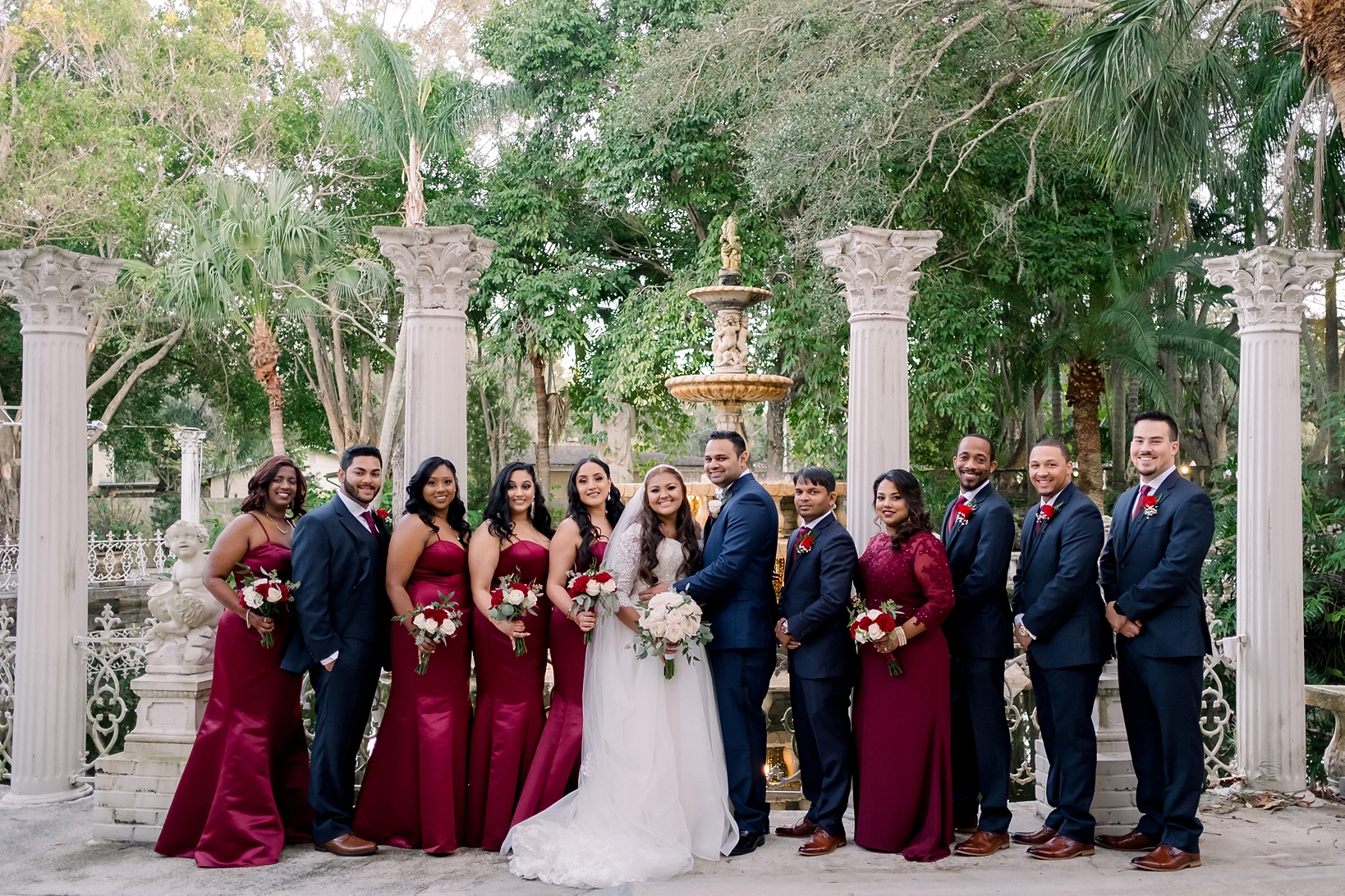 The entire wedding party posing next to the columns of the Kapok Tree in Clearwater, Florida