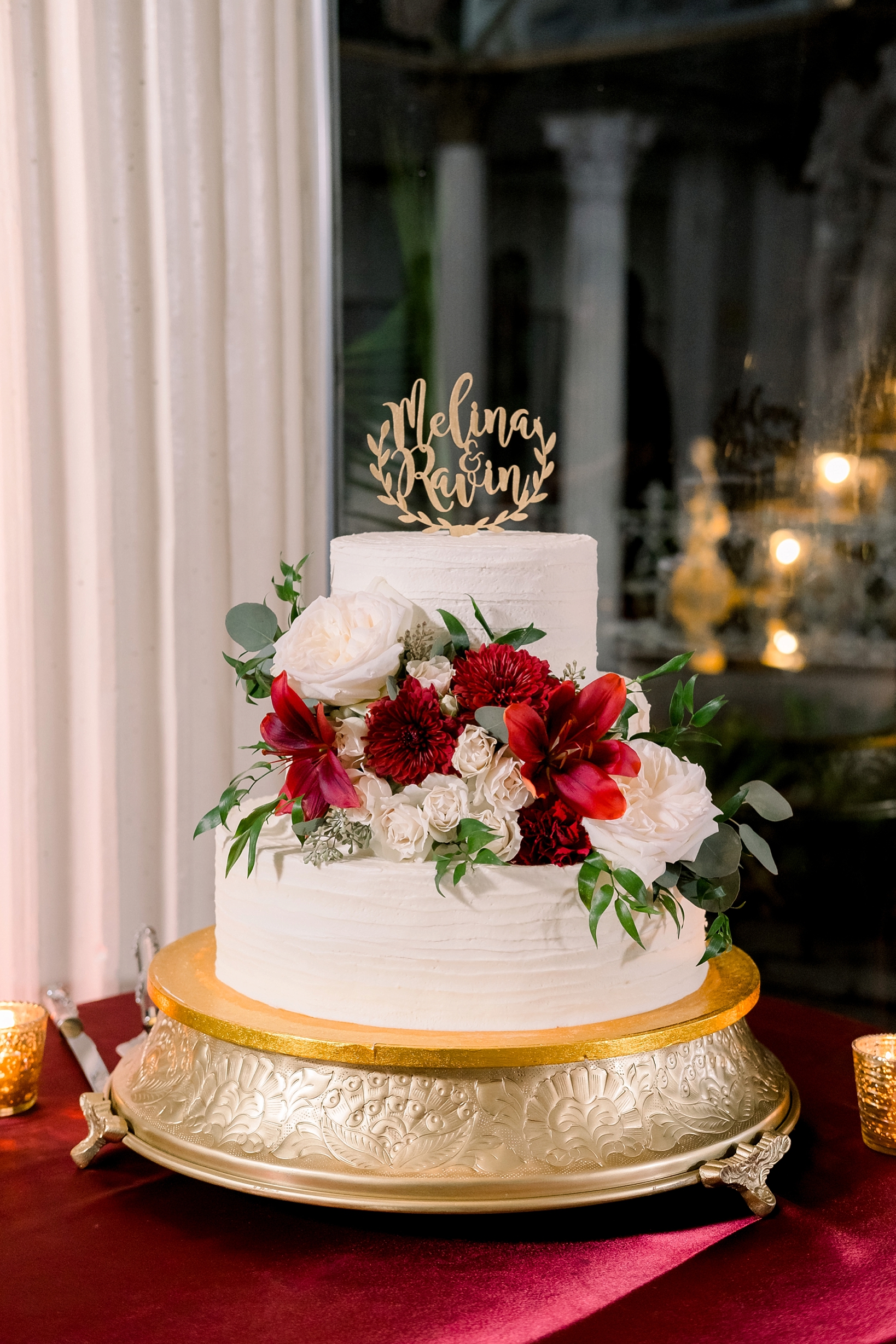 The simple yet luxurious wedding cake covered in full florals and greenery by Sarah & Ben Photography