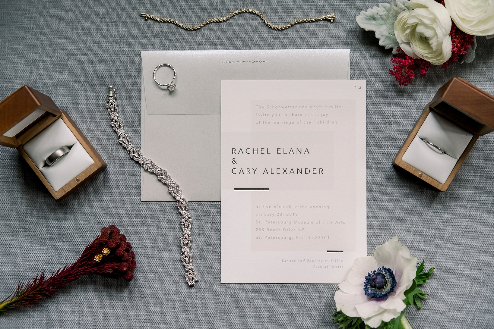 Invitation lay flat with bride's jewelry and florals