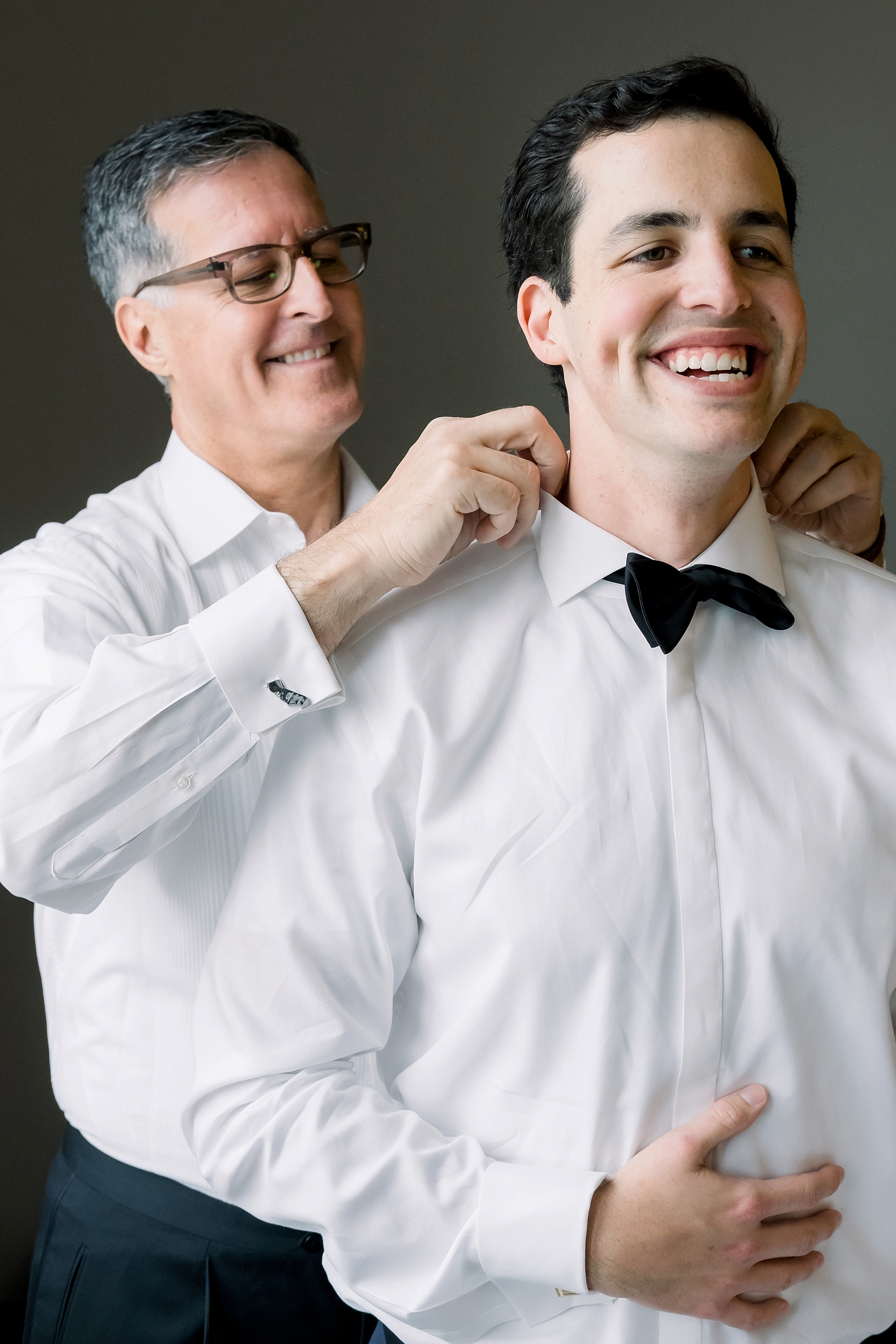 The groom's father helping put his sons bow tie on before the wedding ceremony by Sarah & Ben Photography